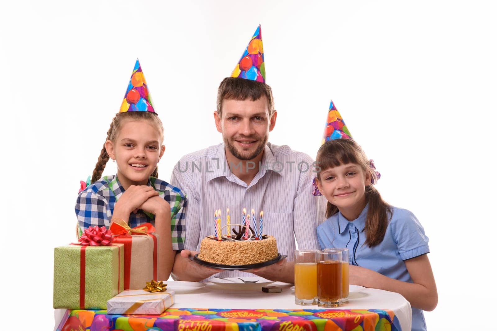 Dad and two daughters with a holiday cake at the table happily look at the frame