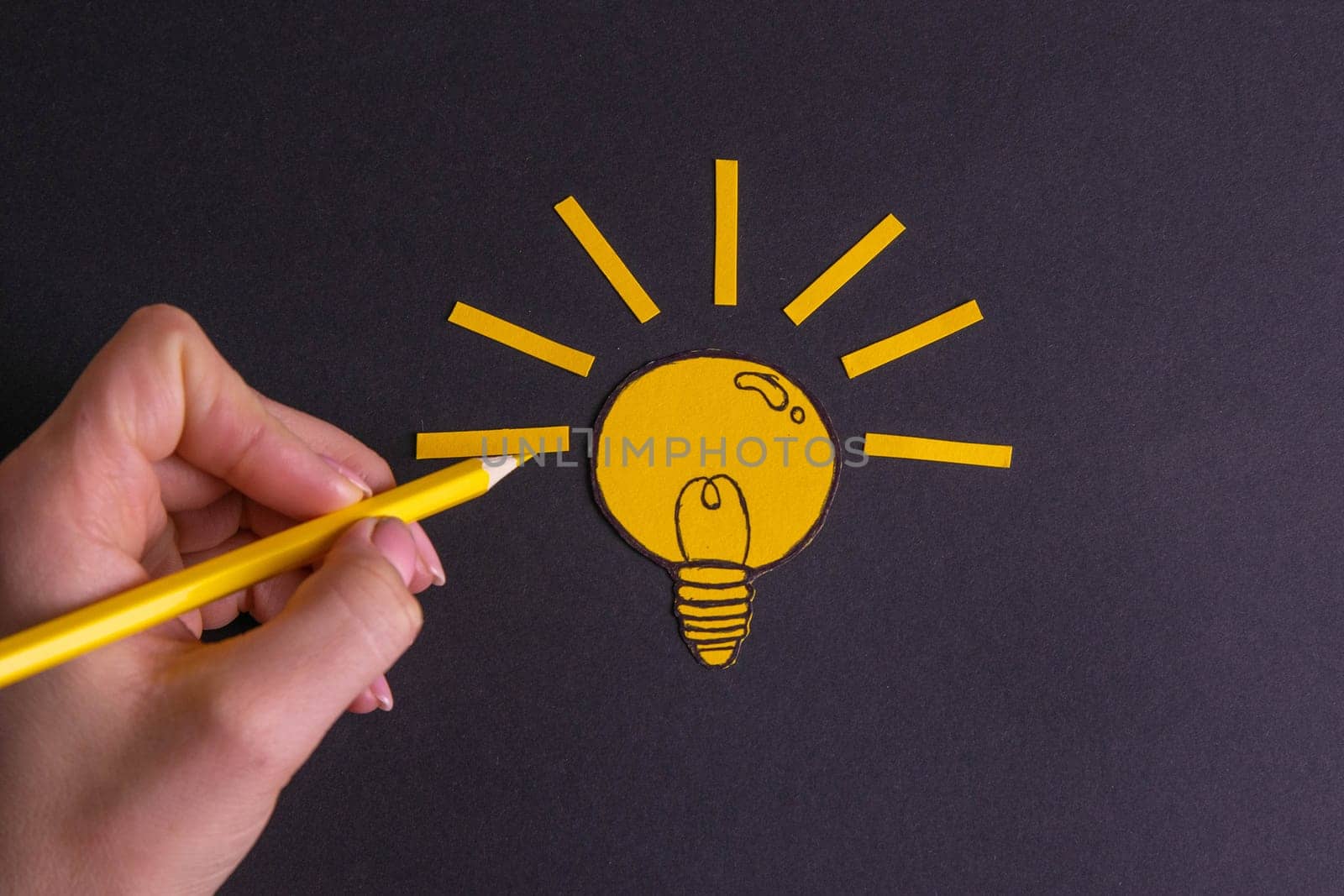 A yellow pencil in hand next to a creative painted light bulb. The concept of innovation and creative ideas.