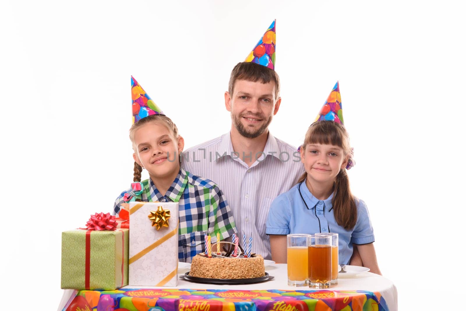 Happy dad and two daughters at the festive table in honor of the birthday