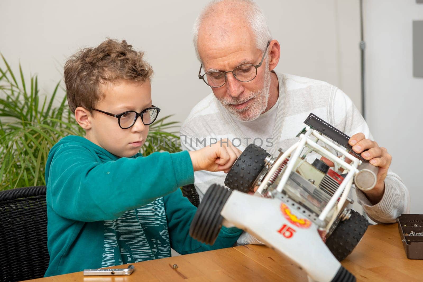 grandpa and son little boy repairing a  model radio-controlled car at home