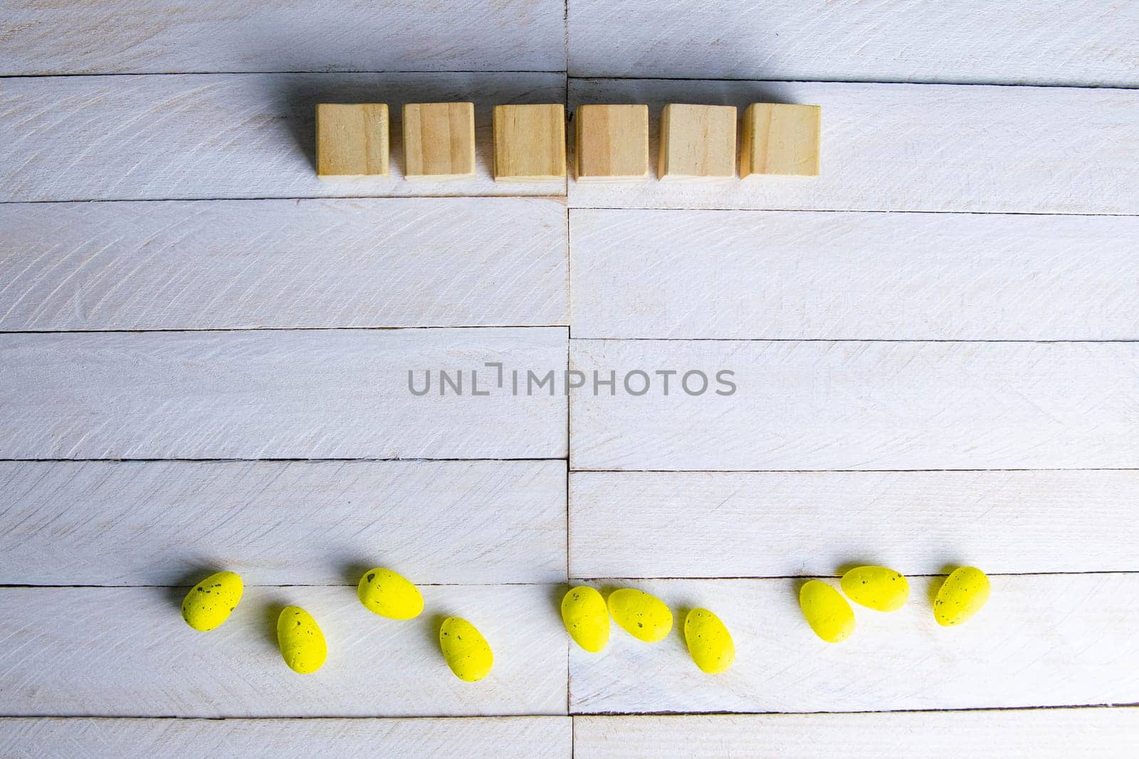 Easter concept. Yellow eggs and wood cubes on a white wooden table.