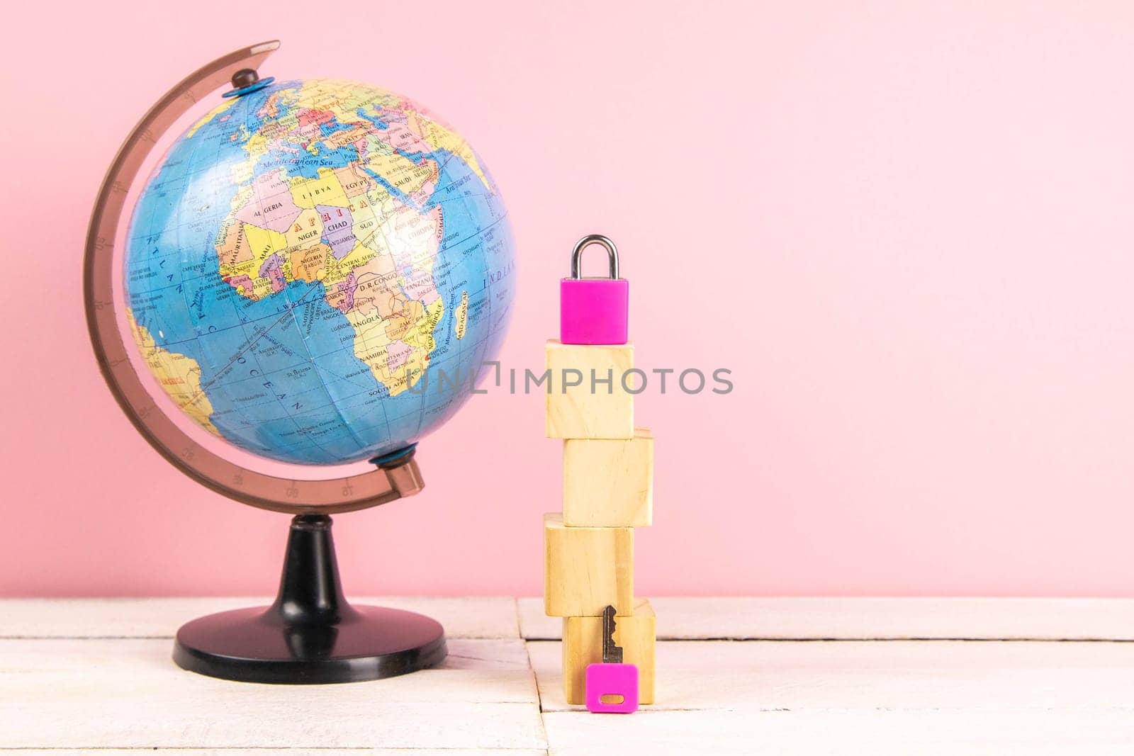Globe and wooden cubes lined in the shape of a house, along with a pink pad and keys. The concept of renting a home.