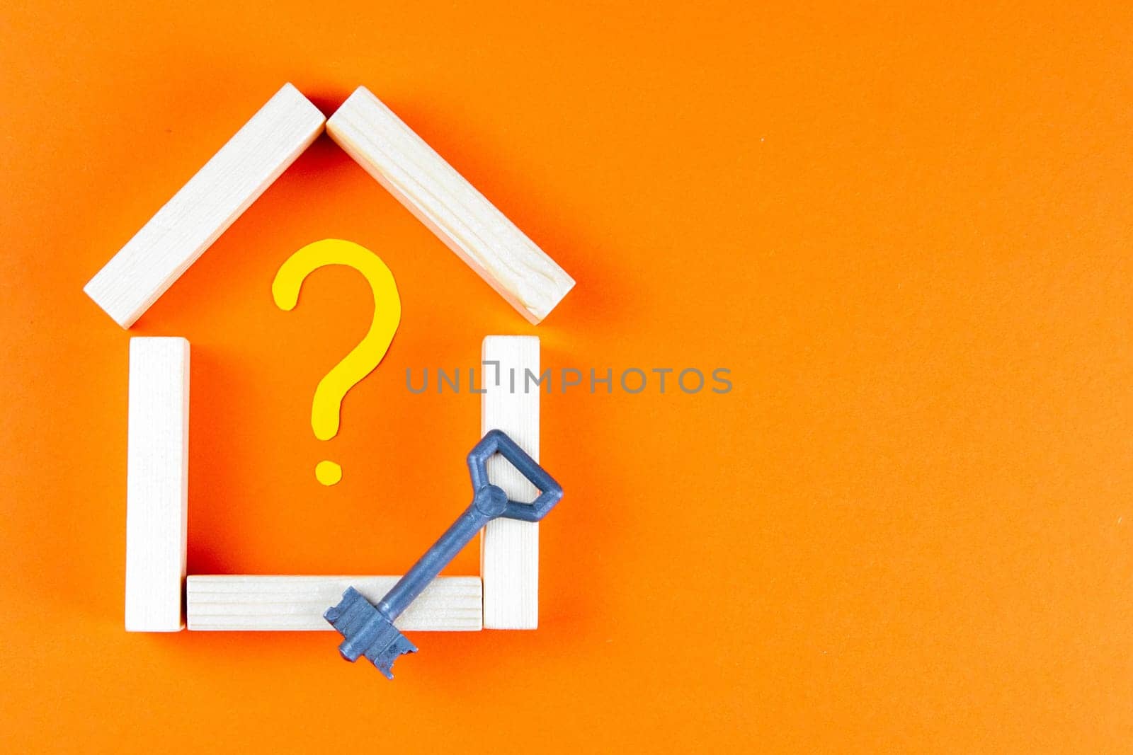 The house is made of wood bars inside a painted question mark, and next to stands the key.