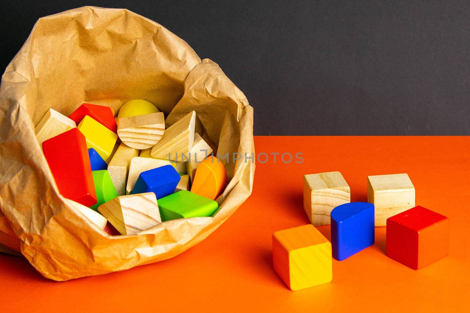 Colorful wooden cubes scattered on an orange table. Most of which is in the craft package.