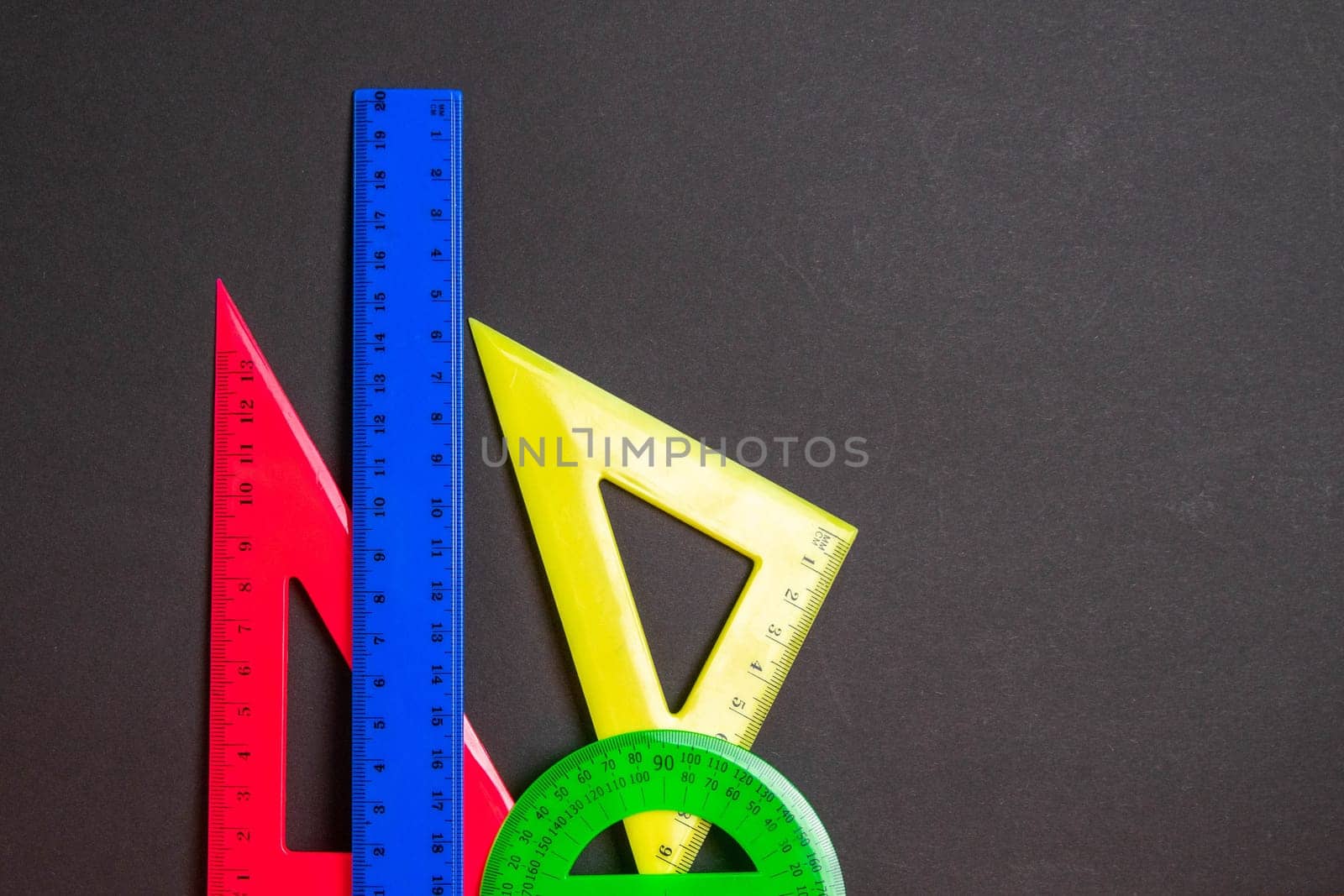 Back to school. Multicolored rulers on a black background. Copy space for text.