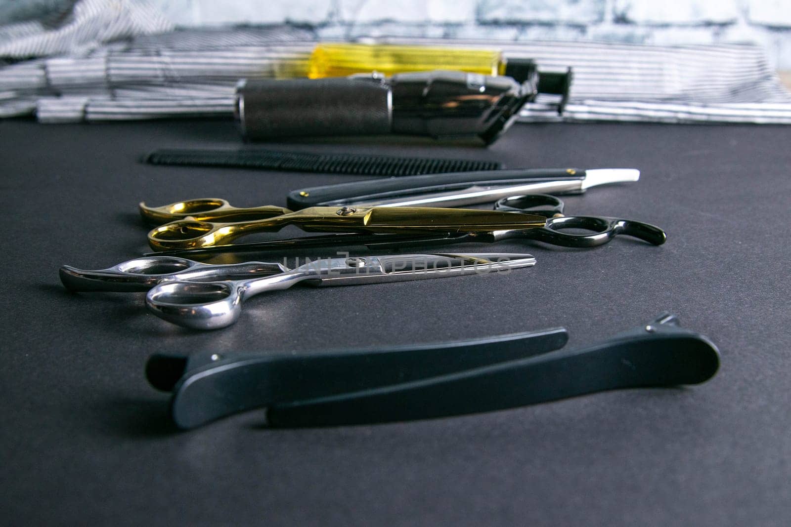 Hairdressing tools, scissors, hair clipper, comb, dangerous razor, hair gel stand on black background.
