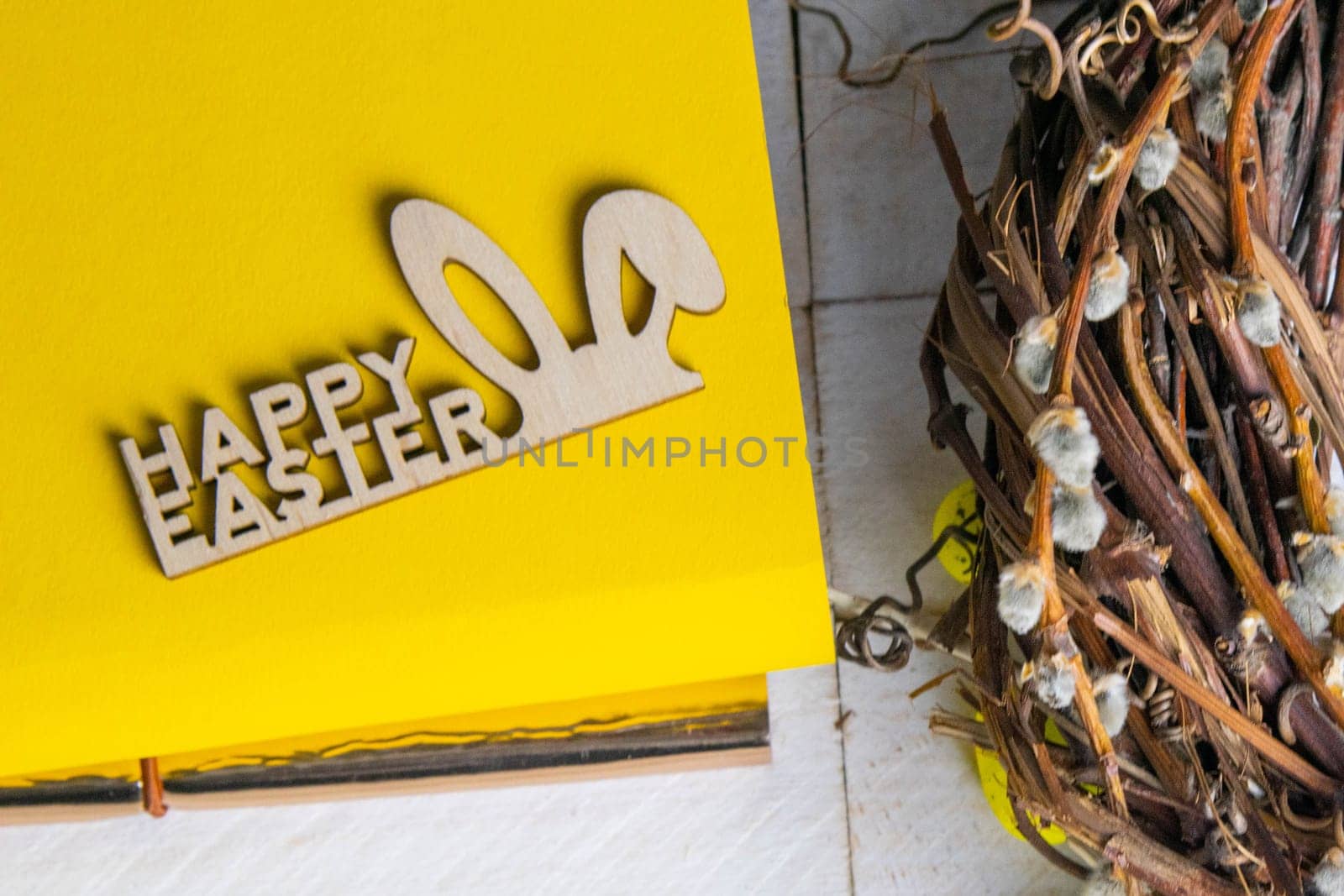 Easter concept. Yellow notepad with a sign of the sorly Easter and a wreath stand on a white wooden table.