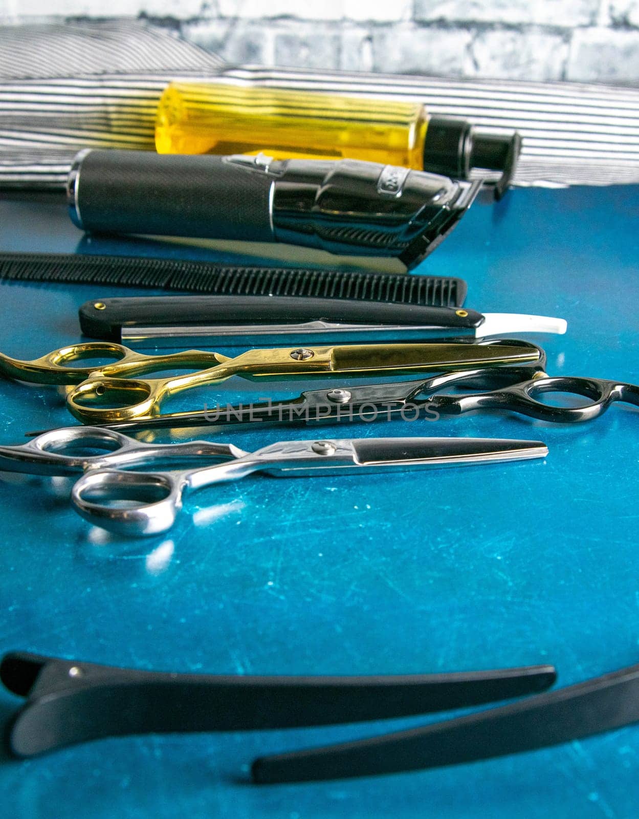 Hairdressing tools, scissors, hair clipper, comb, dangerous razor, hair gel stand on blue background.