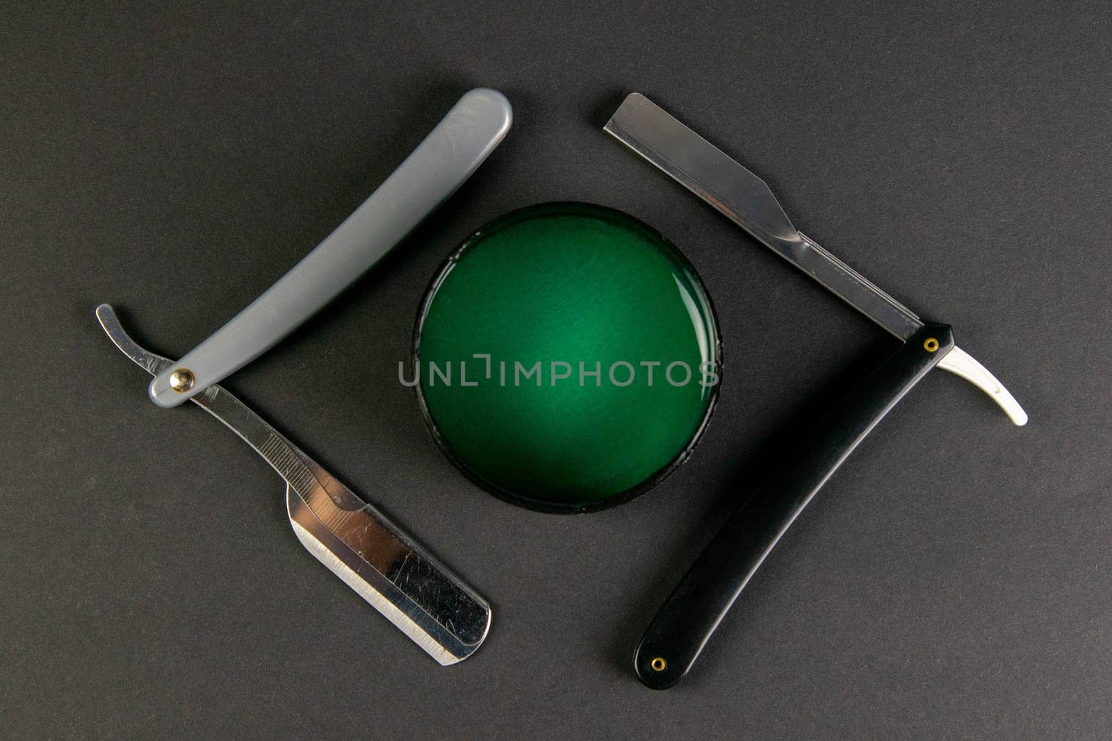 Dangerous razor and a gel for haircuts stand on a black table, the concept of barber shop.