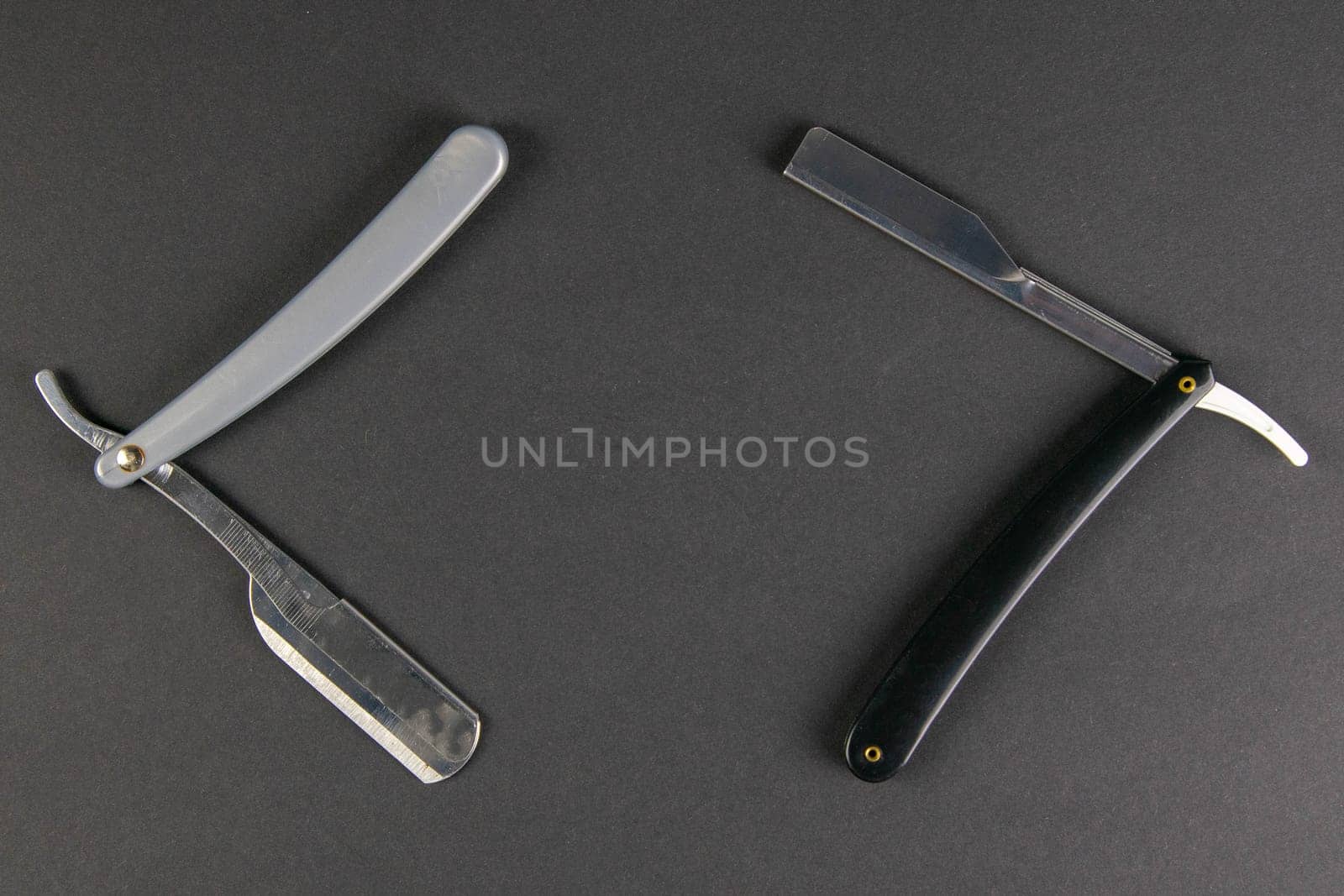 Two dangerous razors on a black table the concept of barber shop.
