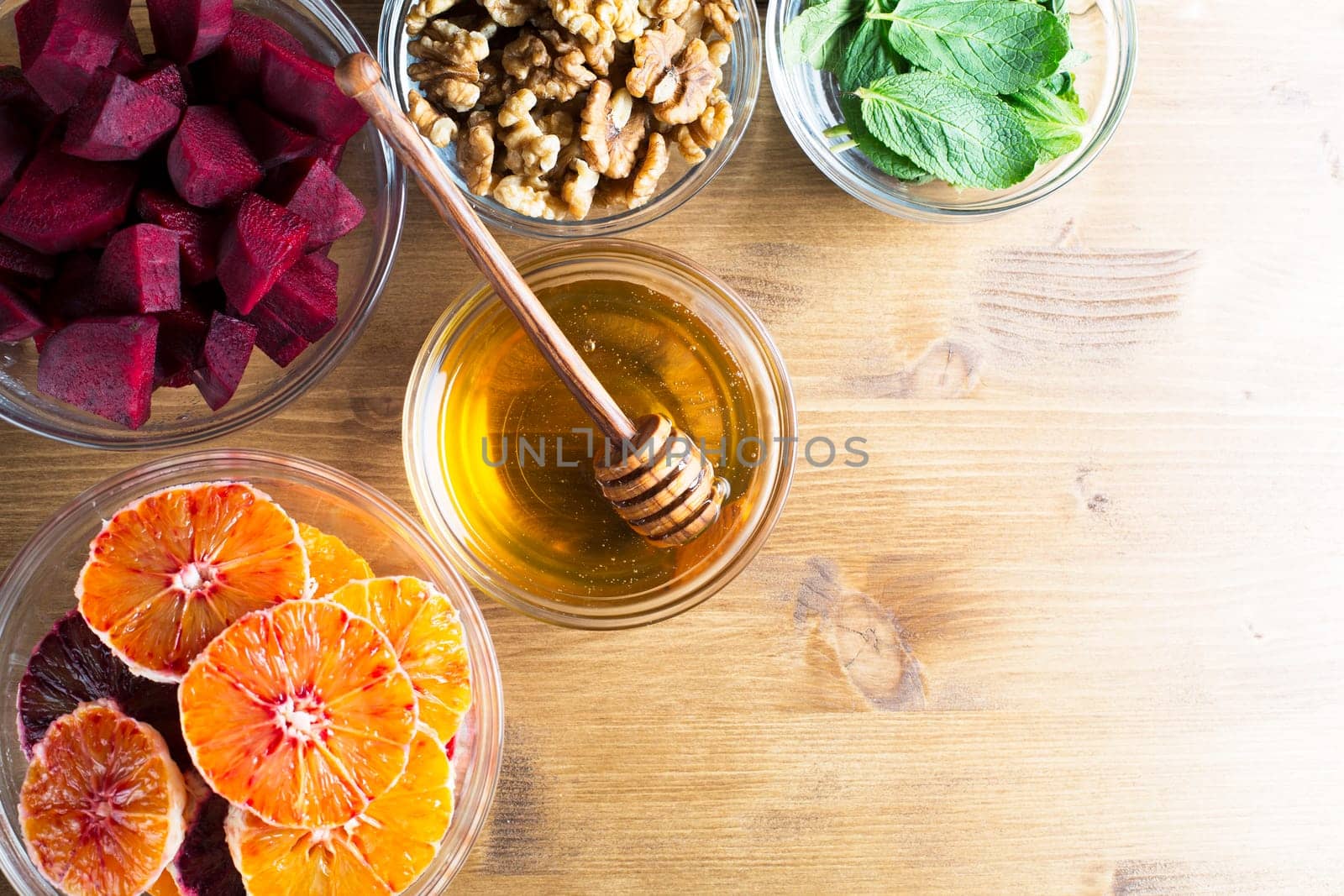 Oranges, honey, beetroot, walnuts and mint leaves on table shot from directly above.