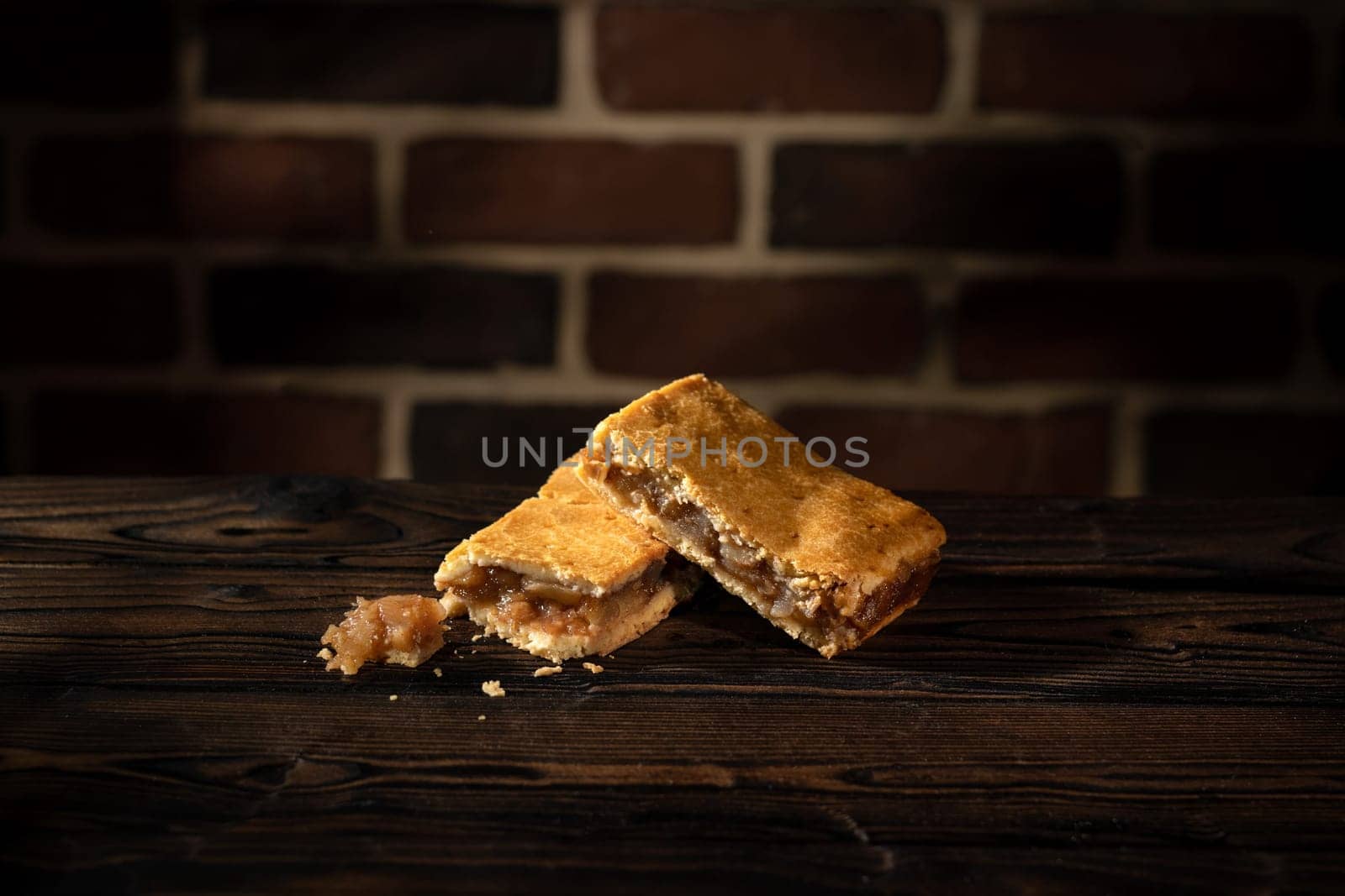 Two apple cake on wooden table and brick wall background