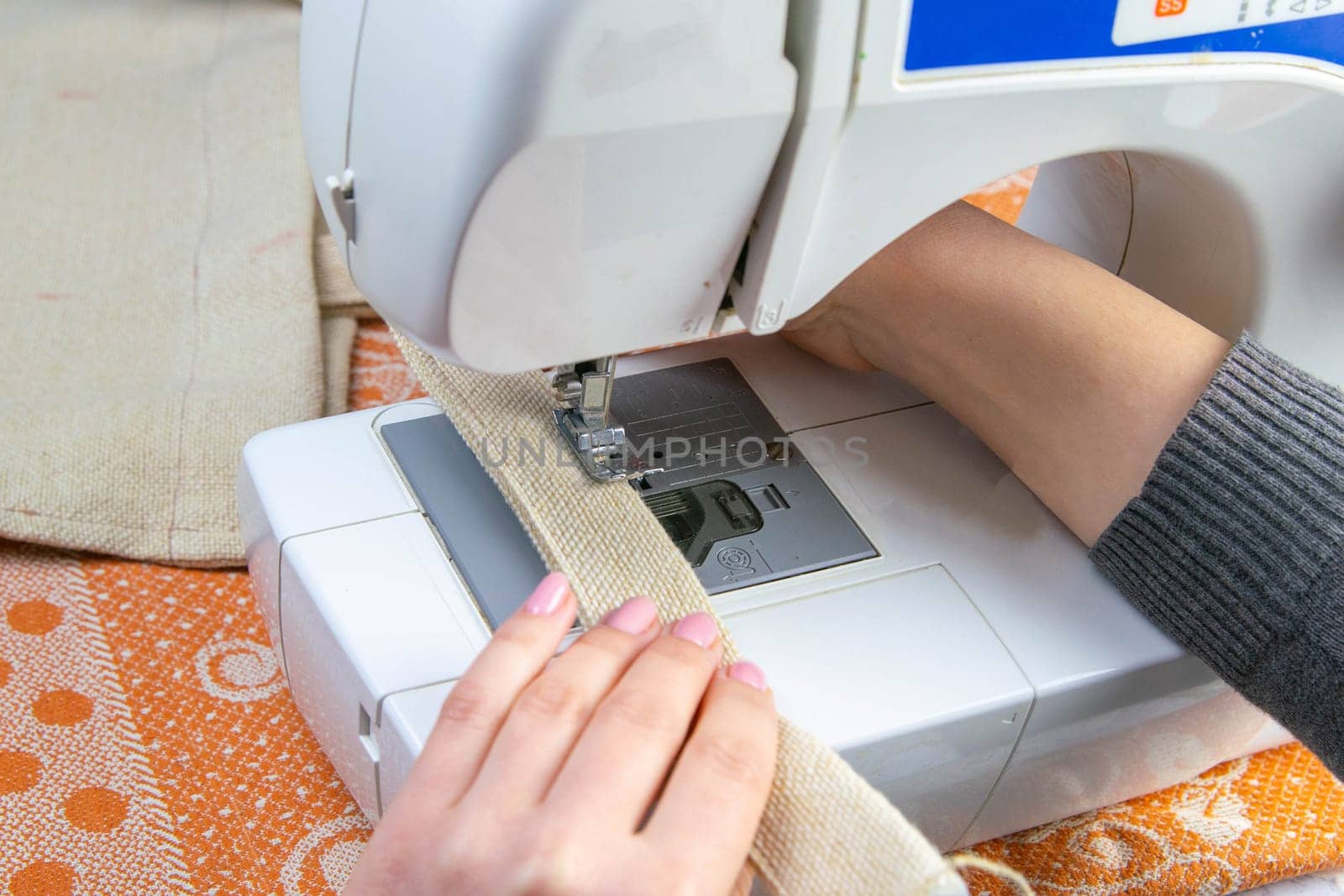 Female hands work on a sewing machine, sewing coffee towel. Close-up.