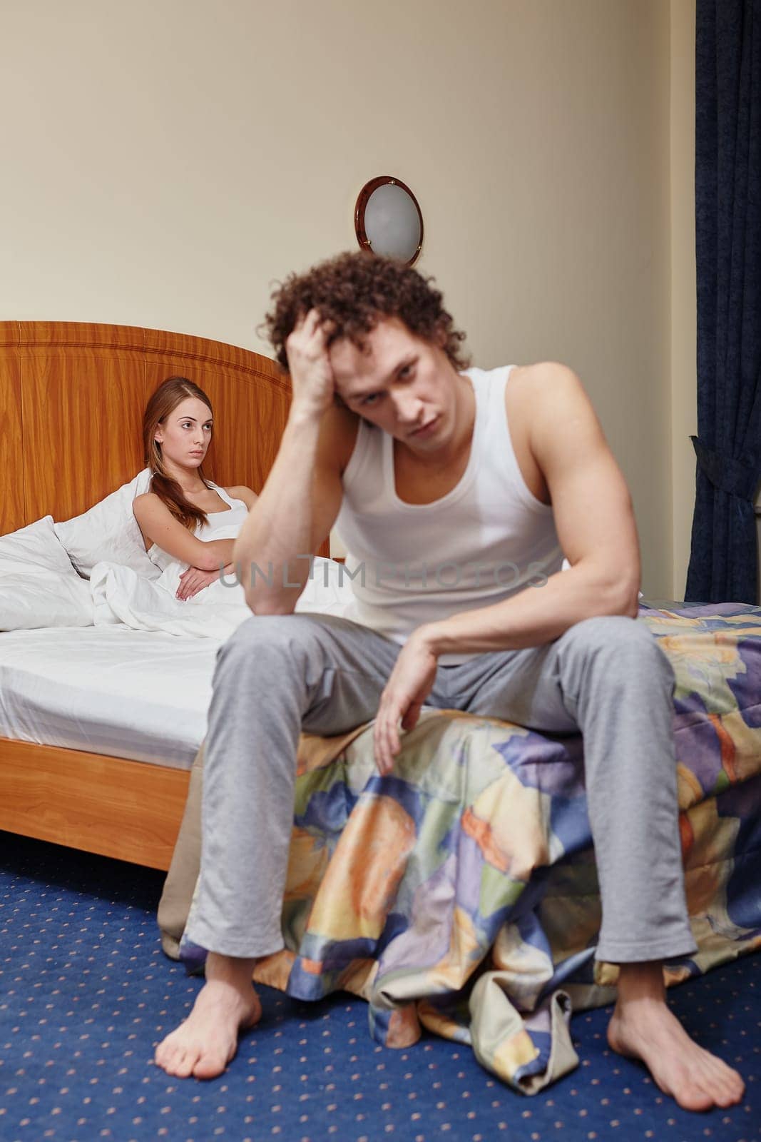 Family problems. Young couple quarrels in bedroom at home. Family conflict. Selective focus on woman