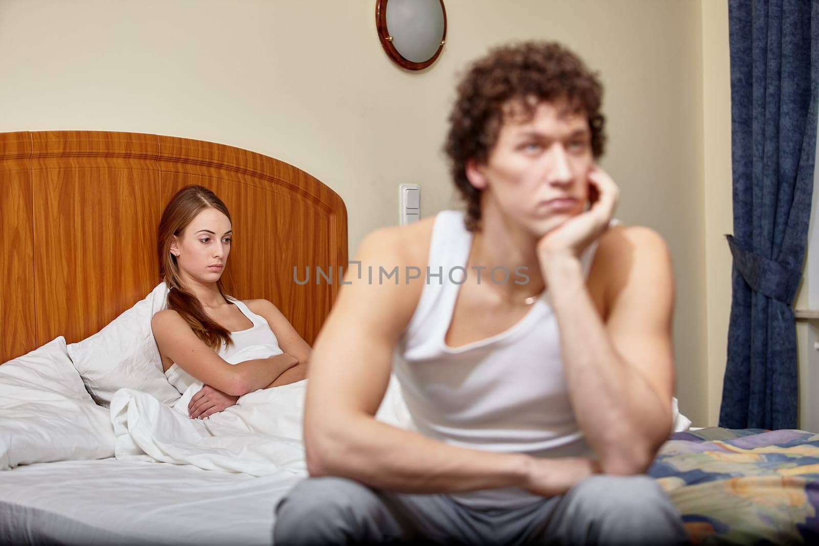 Family problems. Young couple quarrels in bedroom at home. Family conflict. Selective focus on woman