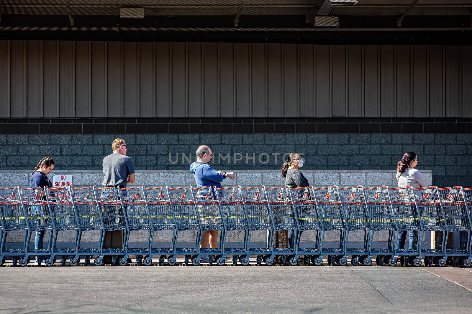 TUCSON, UNITED STATES  - March 29: Five unidentified shoppers practicing social distancing lined up outside retail warehouse store in Tucson during the coronavirus pandemic.. March 29, 2020 in Tucson, Arizona, USA.