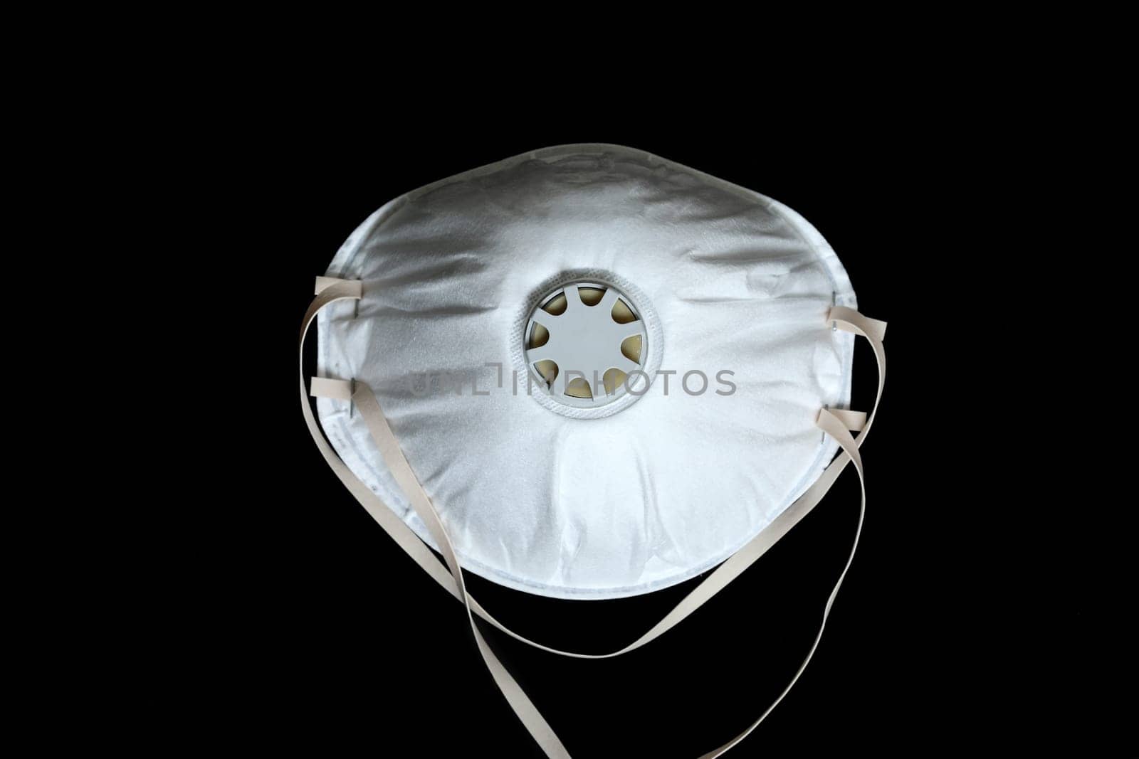 White Surgical Mask FFP2 To Protect Against Virus Infection Coronavirus COVID-19, Isolated On Black Background, Close Up View