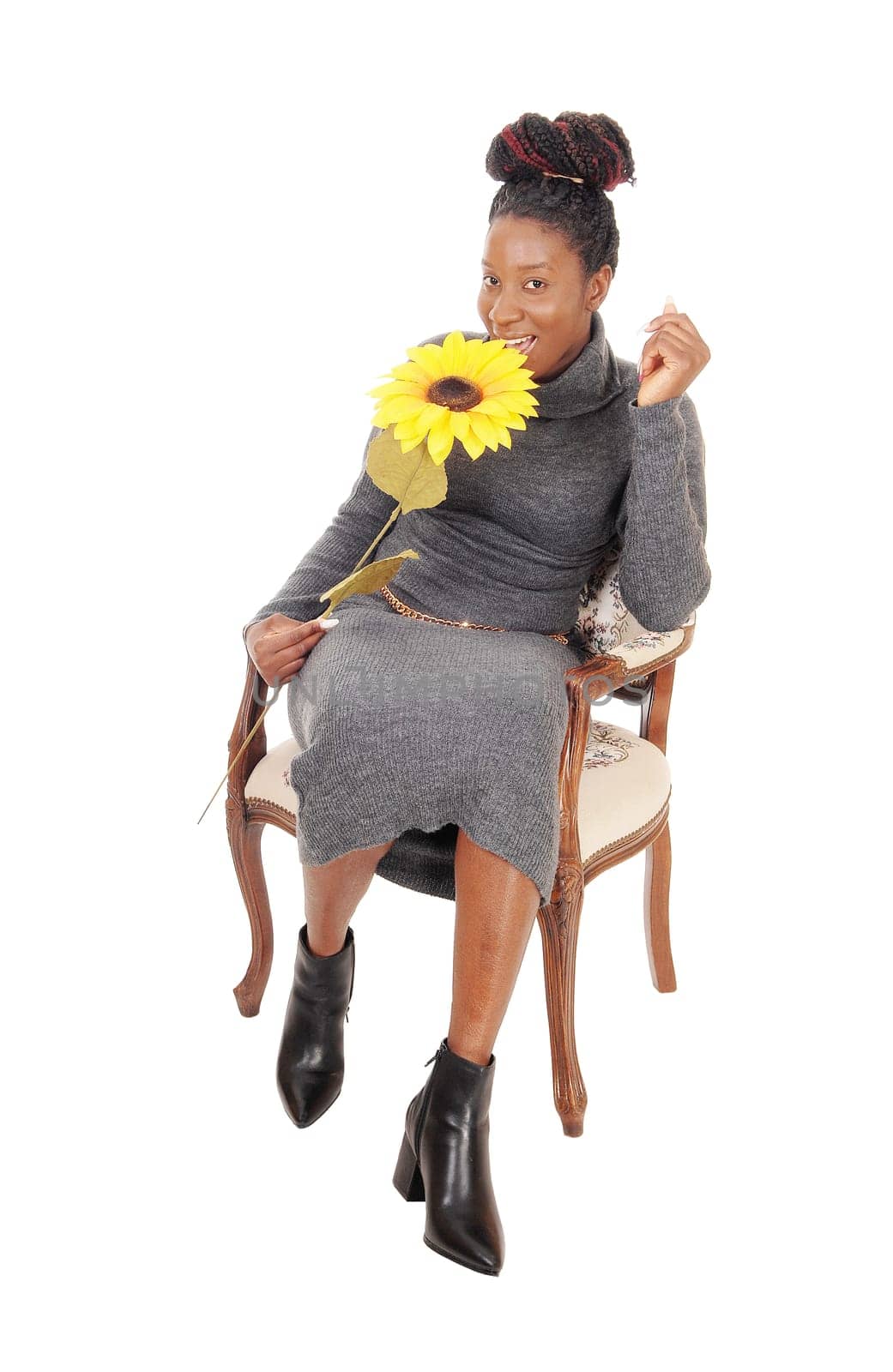 A beautiful young African American woman sitting smiling in a chair.holding a yellow sunflower, isolated for white background.