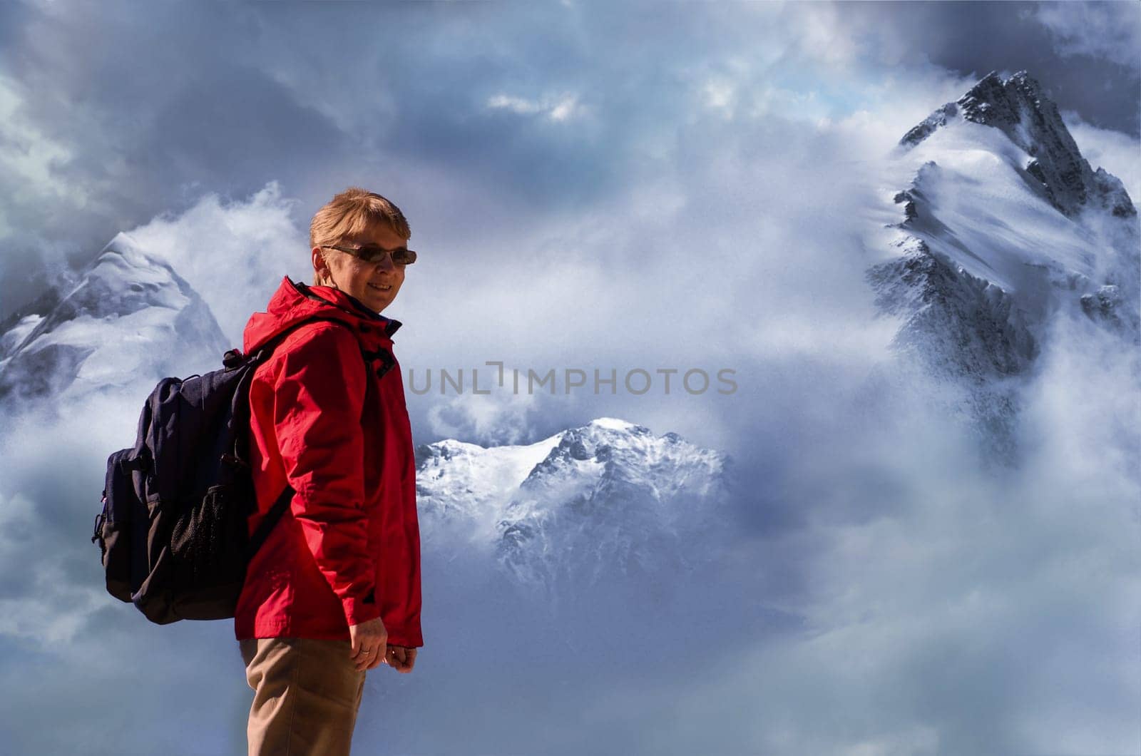 Female caucasian mountain climber in front of peaks with snow and clouds