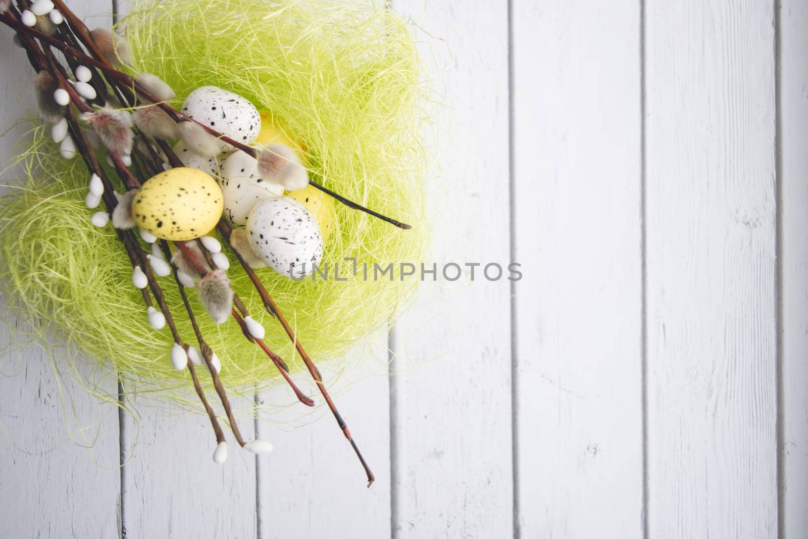 Easter decorations. Willow twigs and decorative Eggs in nests on white wooden background