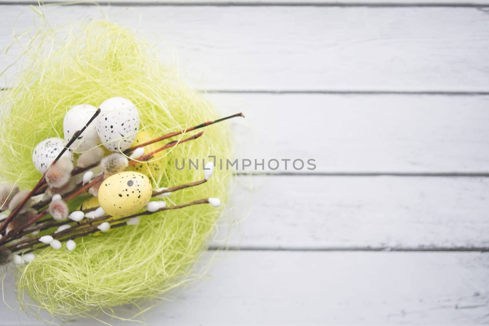 Easter decorations. Willow twigs and decorative Eggs in nests on white wooden background