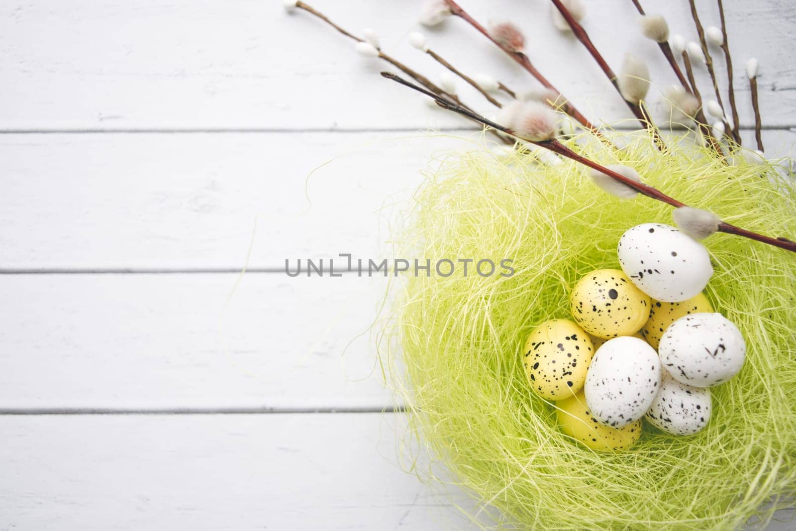 Easter decorations. Willow twigs and decorative Eggs in nests on white wooden background