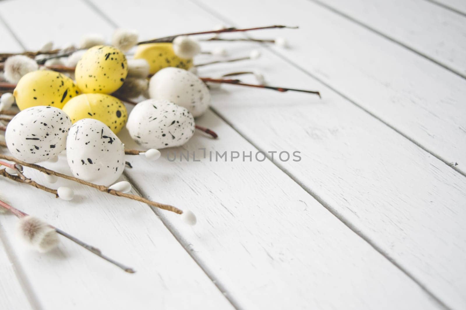 Easter decorations. Willow twigs and decorative Eggs on white wooden background