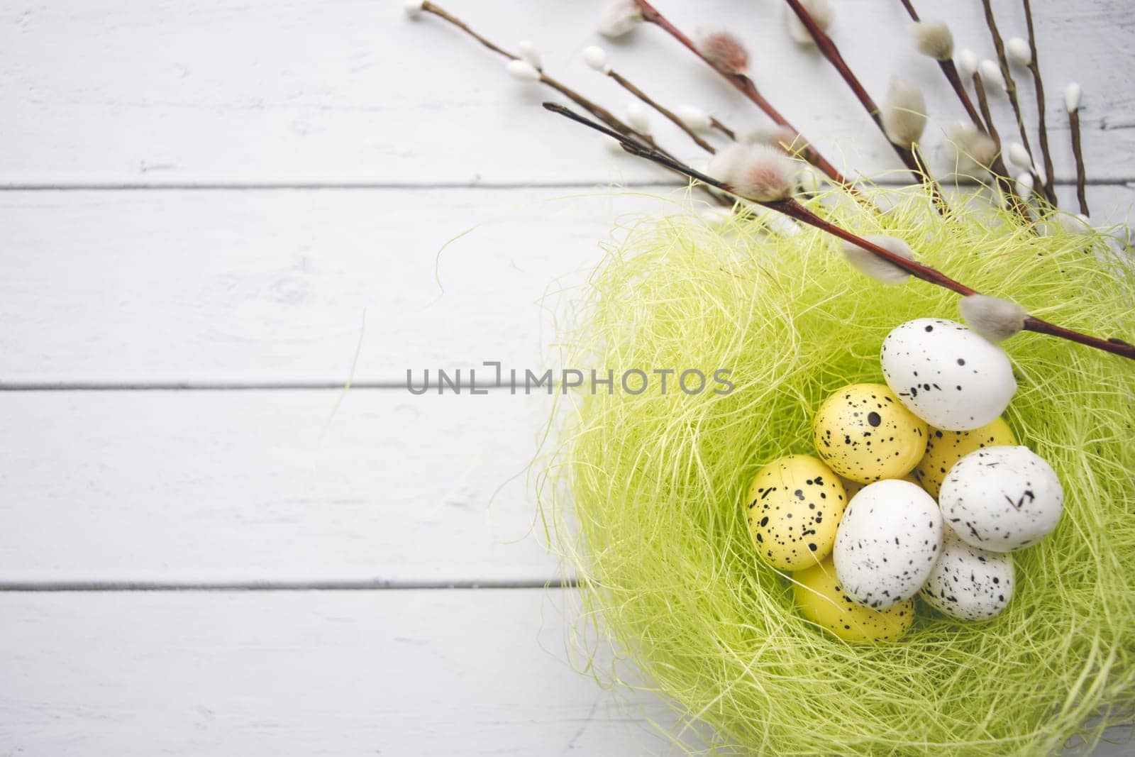 Easter decorations. Willow twigs and decorative Eggs in nests on white wooden background