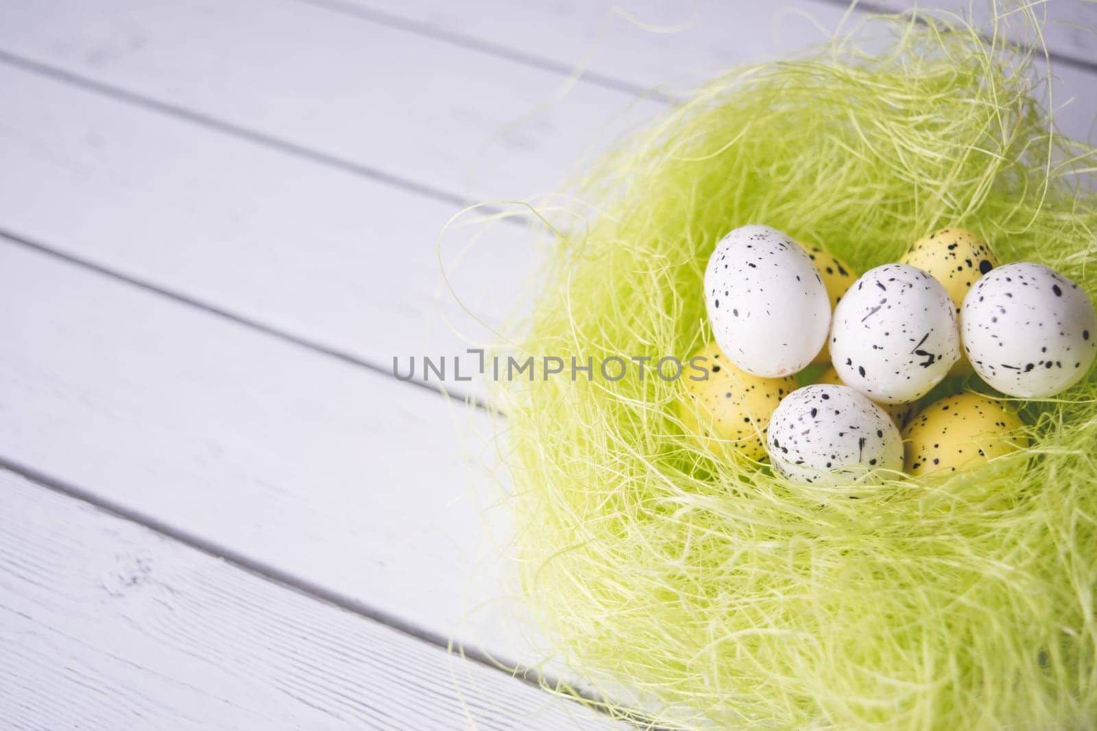 Easter decorations. Eggs in nests on white wooden background