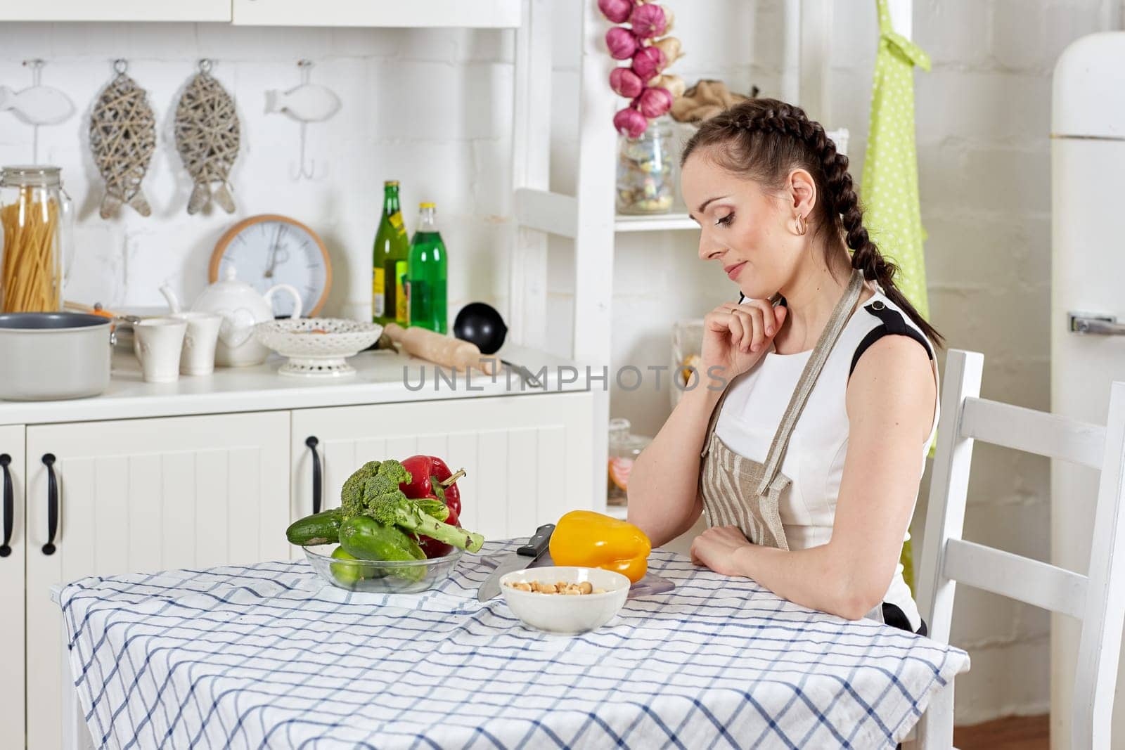 Young woman in an apron is cooking healthy food in the kitchen.