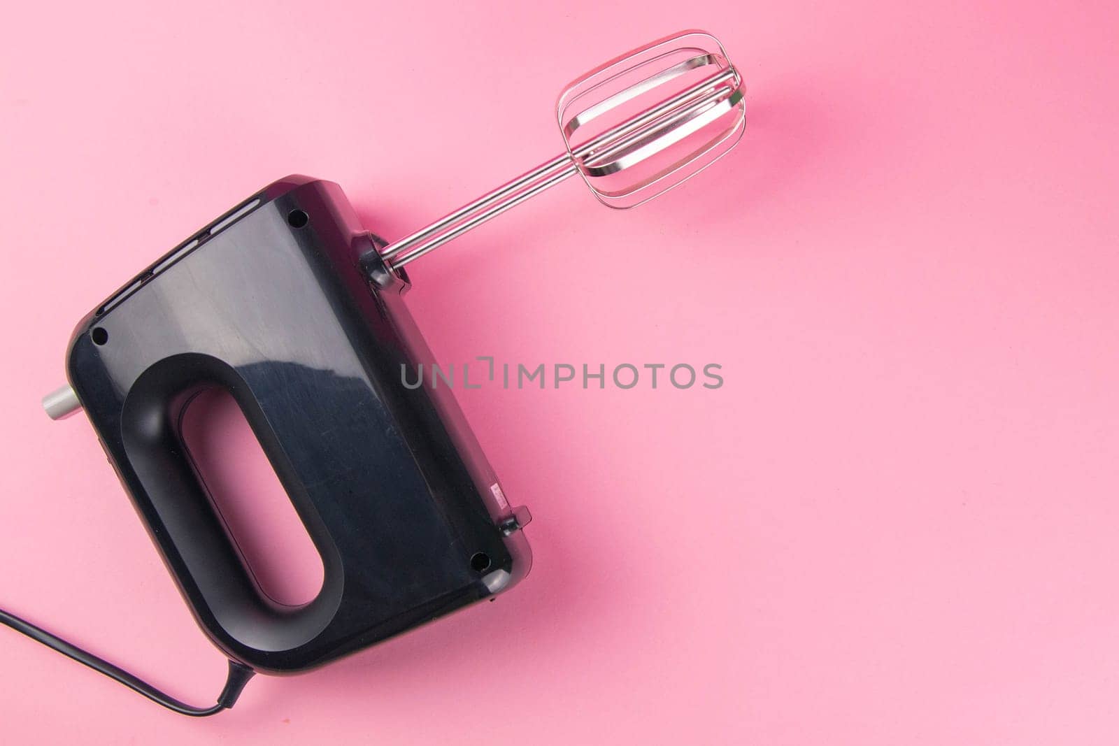 Kitchen electric hand mixer for mixing whip or eggs isolated on pink background. Top views with clear space