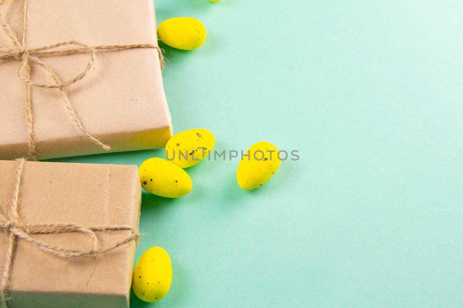 Two easter gifts, yellow eggs on a mint background close-up. Easter background.