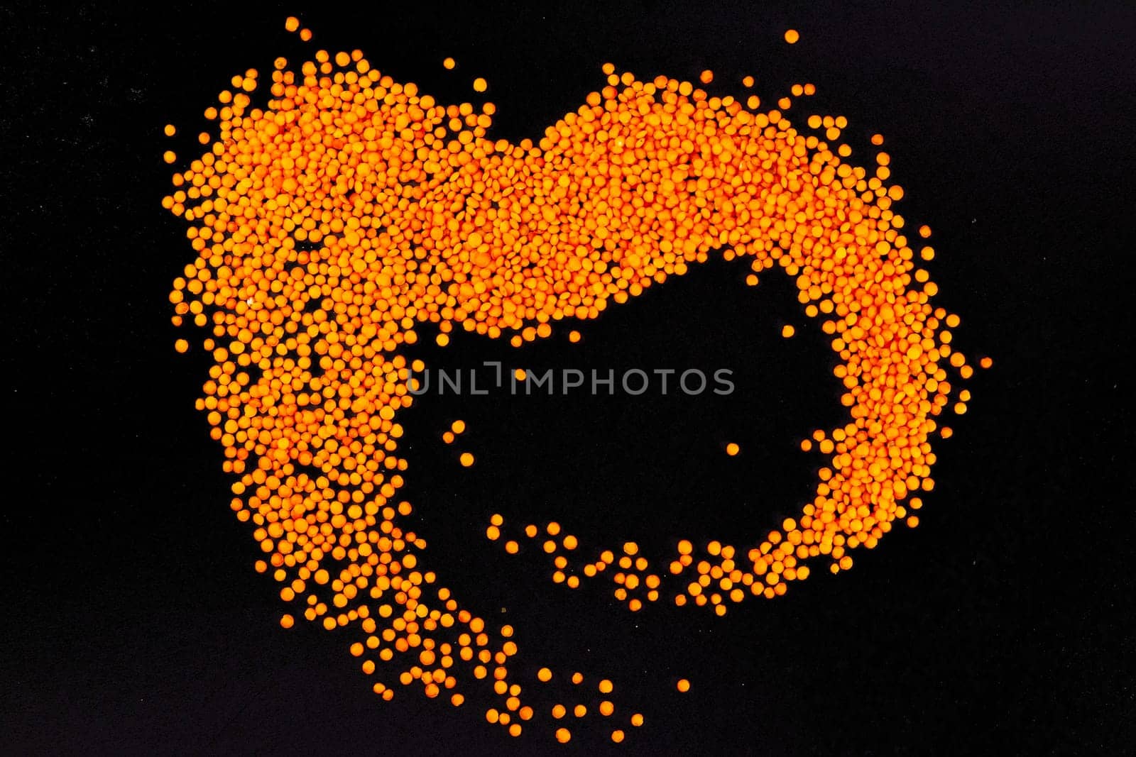 Red lentils on a black background. Top views.