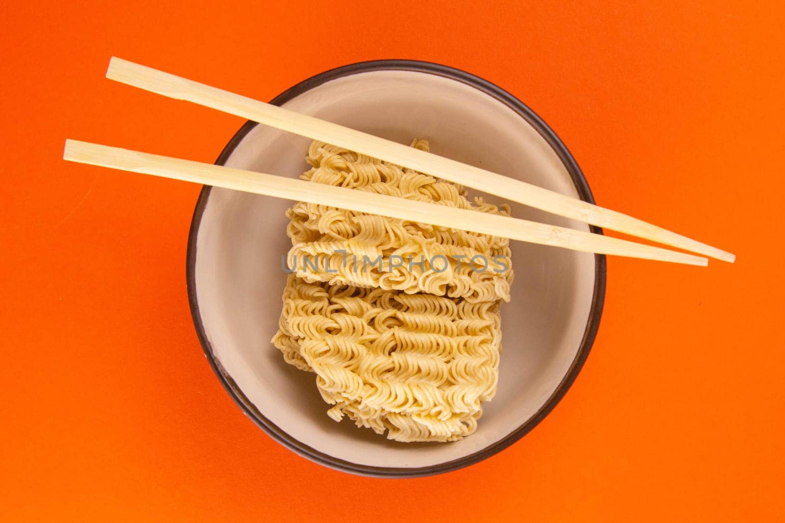 Instant noodles with wood sticks. Asian fast food on a orange background close-up. Top views.