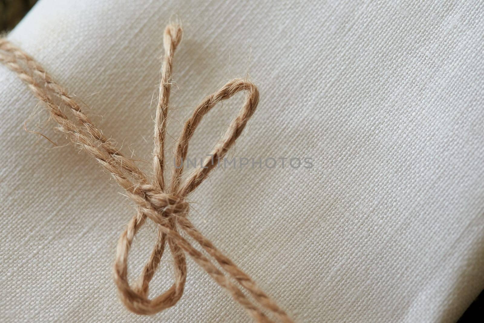 Twine tied in a bow. Close-up. Fabric background