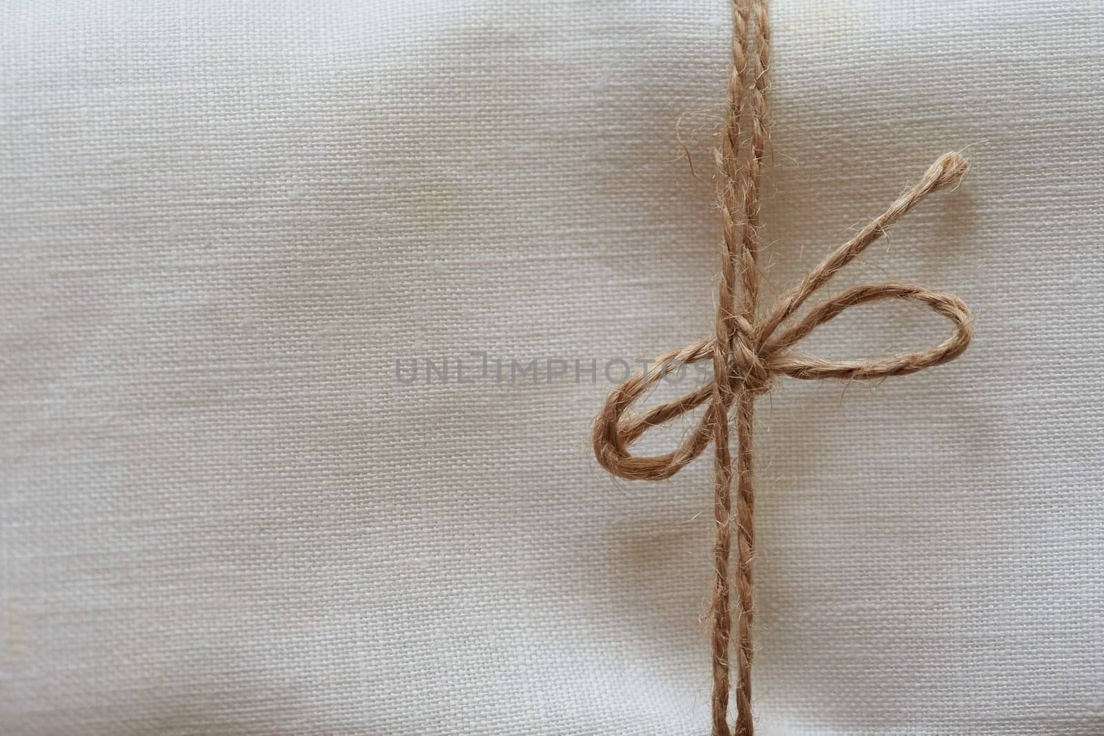 Twine tied in a bow. Close-up. Fabric background