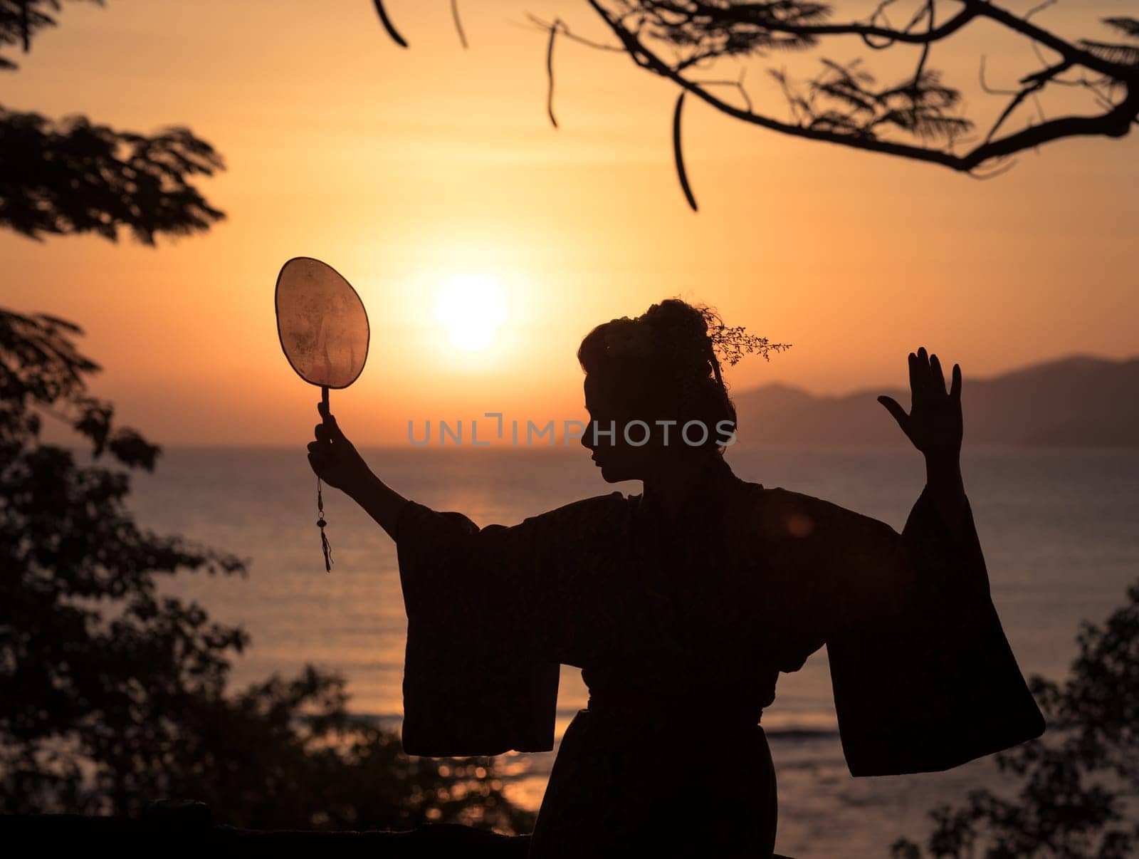 Silhouette of Japanese Geisha in kimono with fan at sunrise