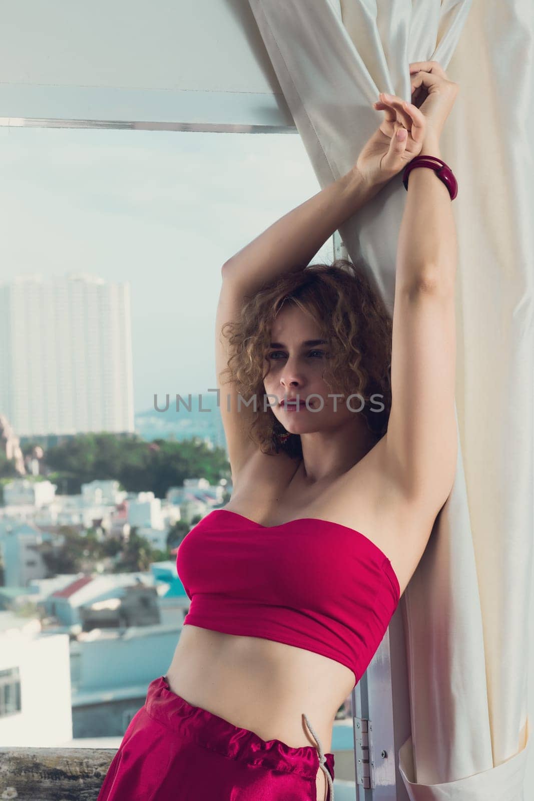 Fashion style portrait of a beautiful woman in red on a balcony