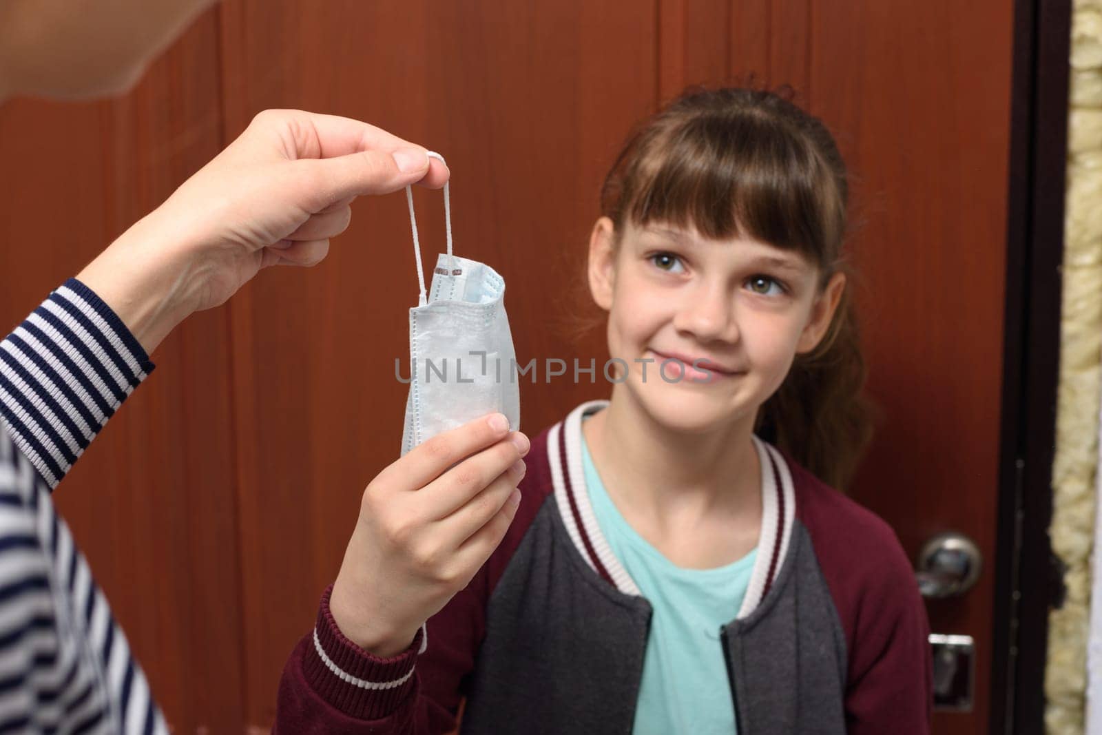 A girl takes a protective medical mask from her mother’s hand