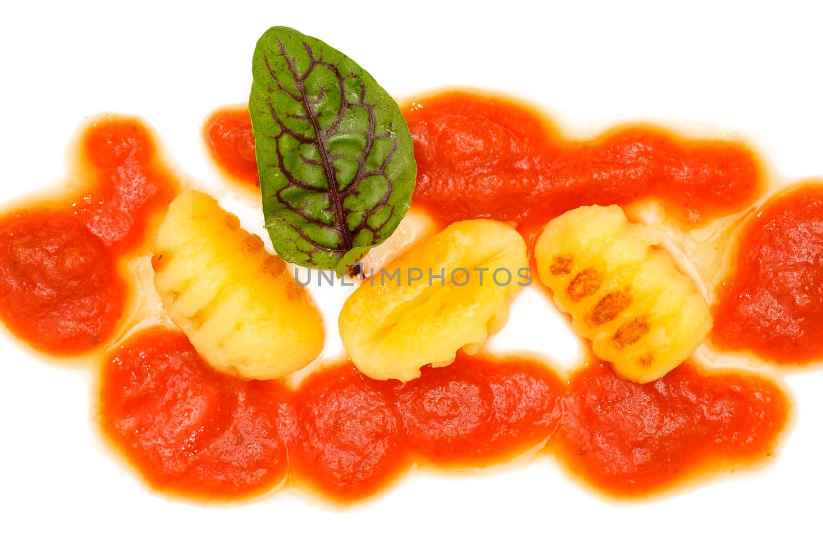 Roasted gnocchi with tomato sauce and red vein dock on white