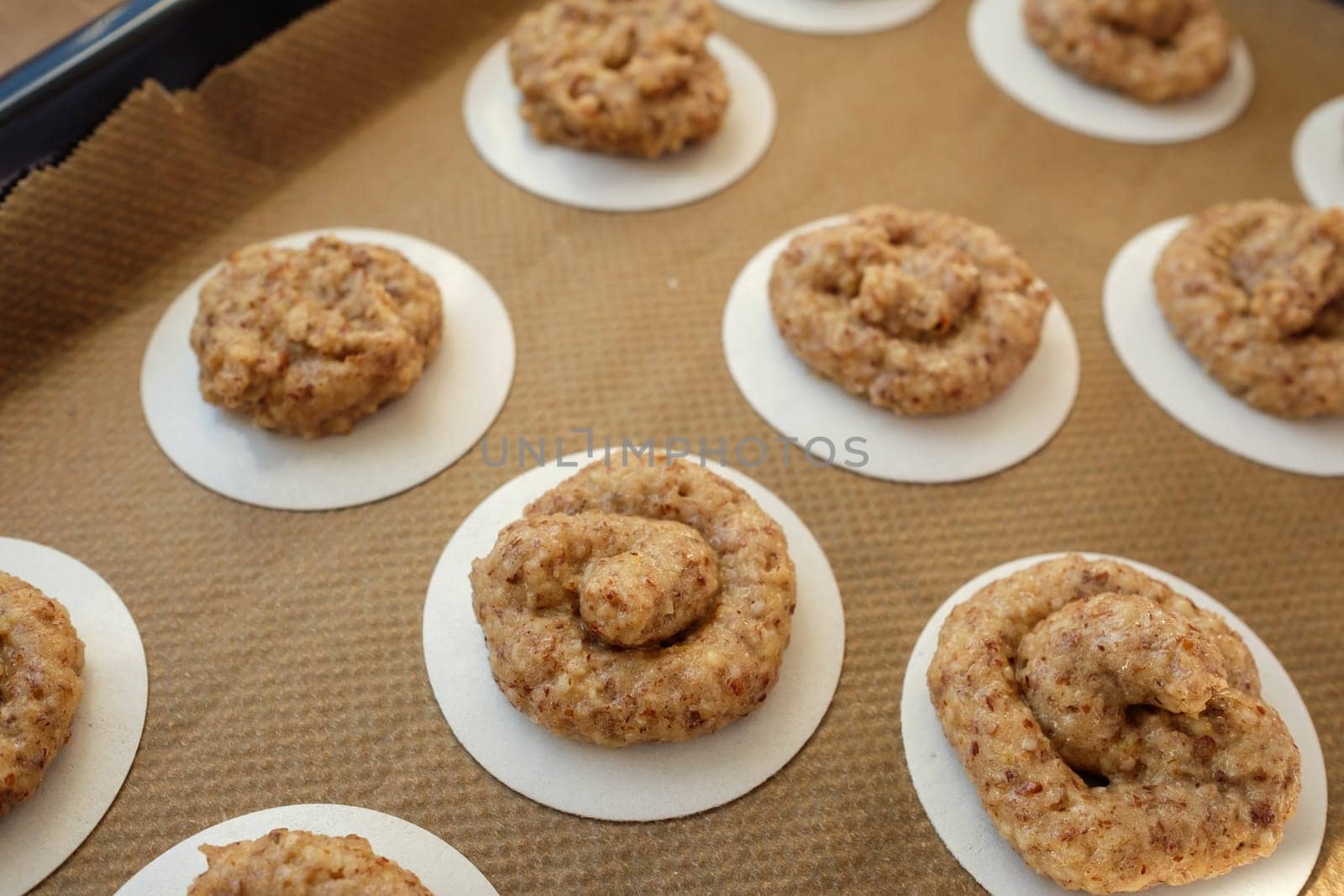 Raw hazelnut macaroons on griddle and baking paper