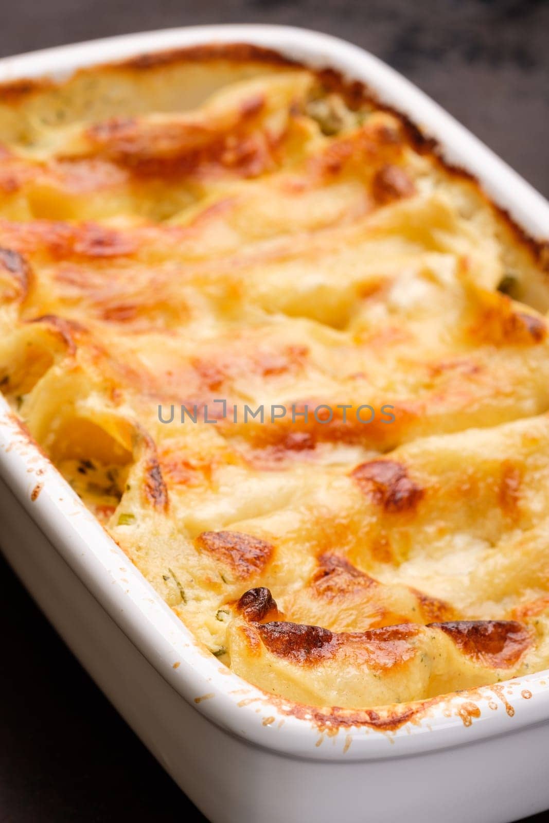 Cannelloni gratin filled with cheese in vertical format