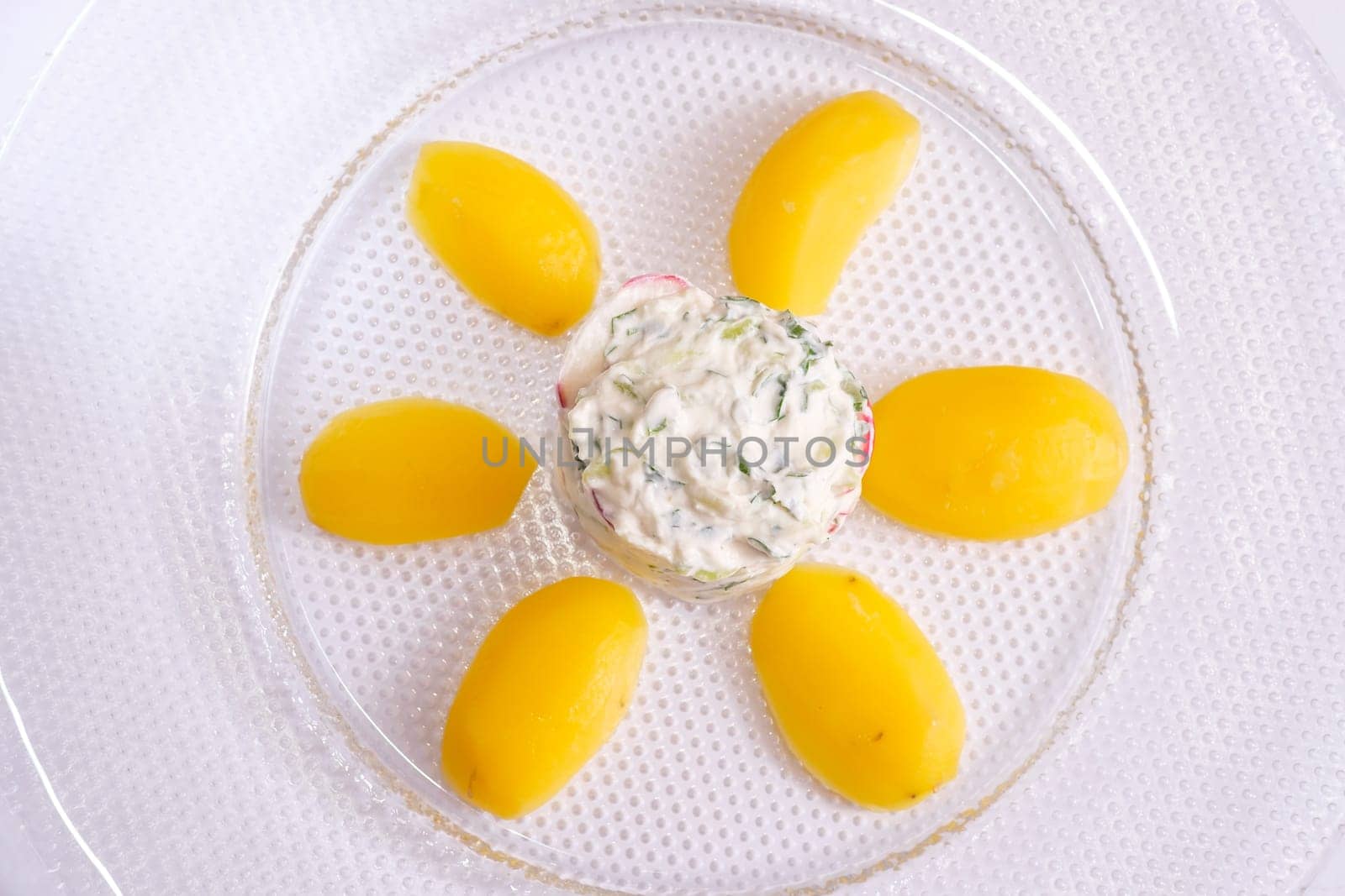 Top view glass plate with potatoes cucumber radish and curd