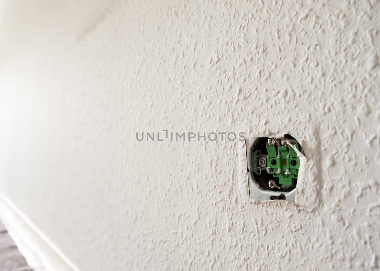 Open socket at a wall with woodchip wallpaper in back lit
