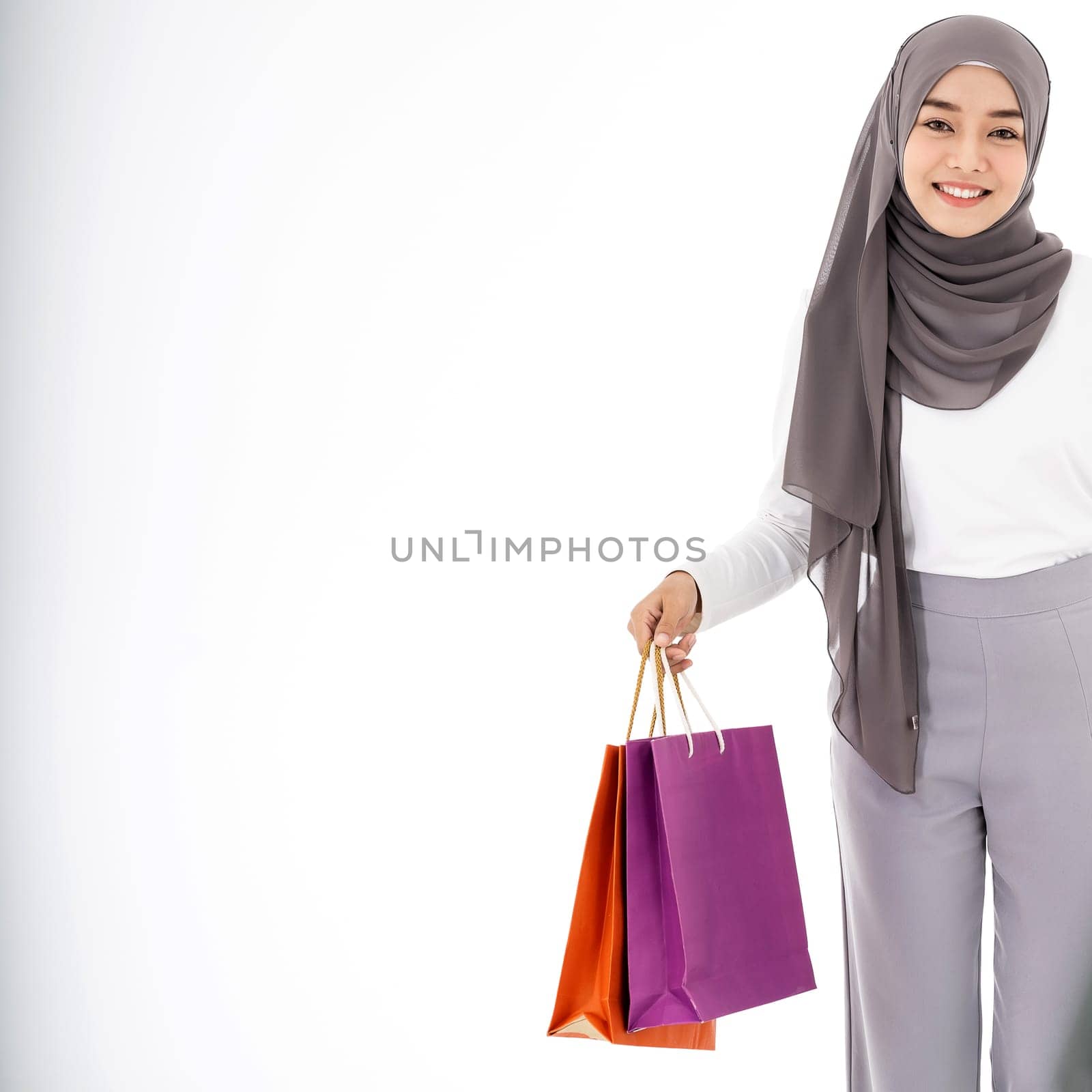 Closeup Confident happy smiling female muslim woman with shopping bag. Studio shot on white background. Using for sale consumerism and shopaholic concept.