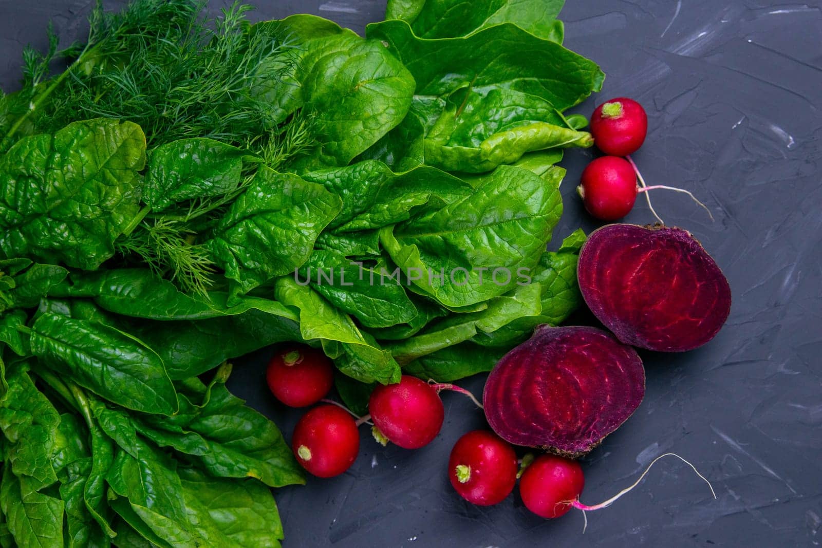 Fresh vegetables and greens radish, spinach, beet on a black background. Top views, clouse-up