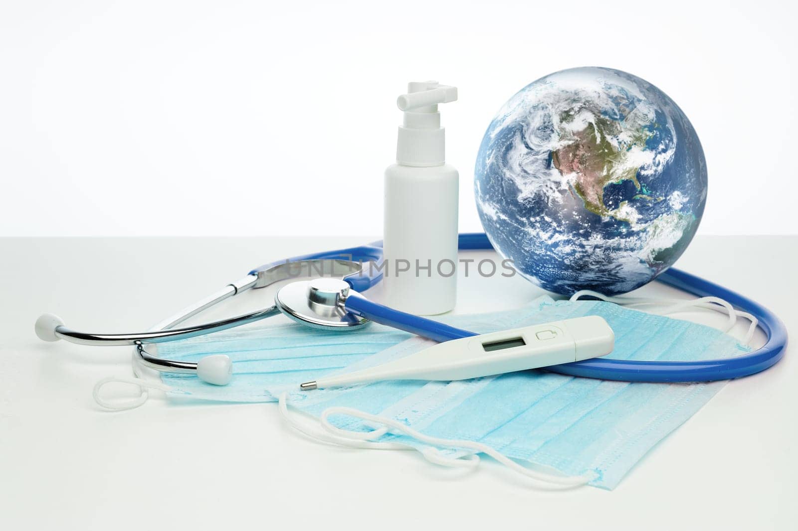 COVID-19. World globe with stethoscope, medical masks, sanitizer, thermometer on white background. Global quarantine, infection prevention, coronavirus. Elements of this image furnished by NASA