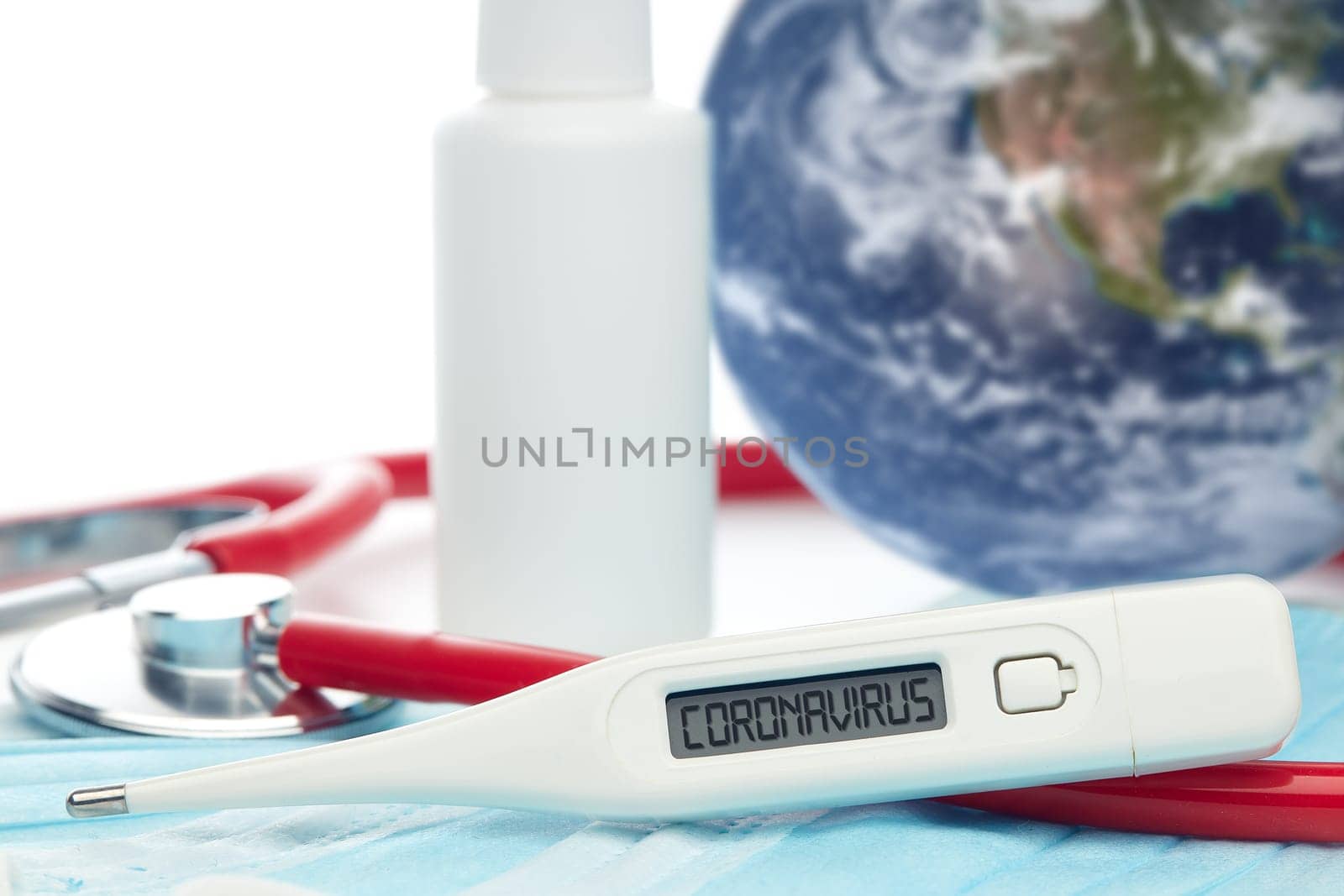 COVID-19. World globe with stethoscope, medical masks, sanitizer, thermometer on white background. Global quarantine,  coronavirus. Elements of this image furnished by NASA. Selective focus on thermometer