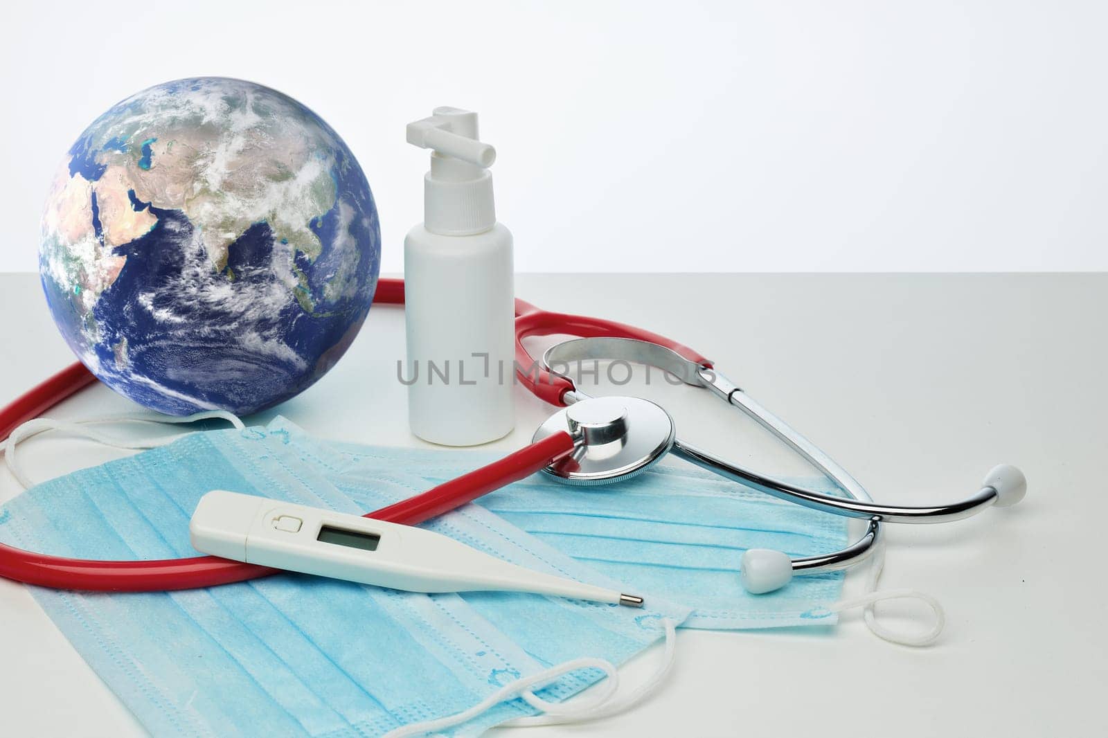 COVID-19. World globe with stethoscope, medical masks, sanitizer, thermometer on white background. Global quarantine, infection prevention, coronavirus. Elements of this image furnished by NASA
