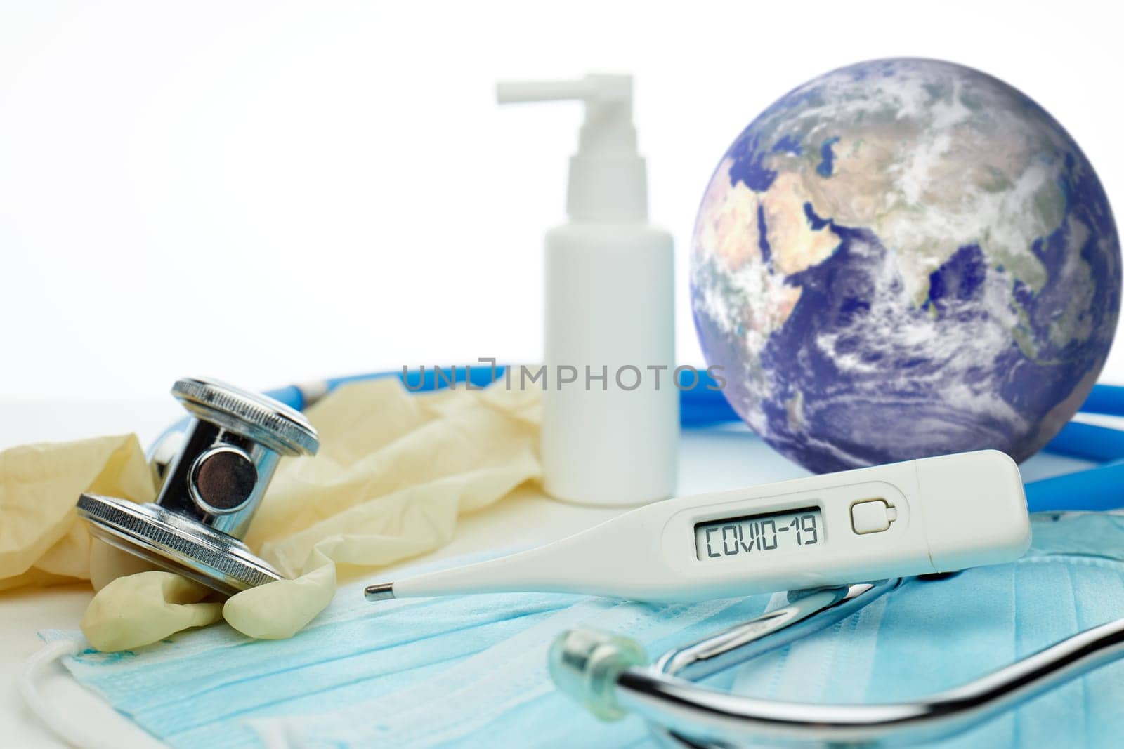 COVID-19. World globe with stethoscope, medical masks, sanitizer, thermometer on white background. Global quarantine,  coronavirus. Elements of this image furnished by NASA. Selective focus on thermometer